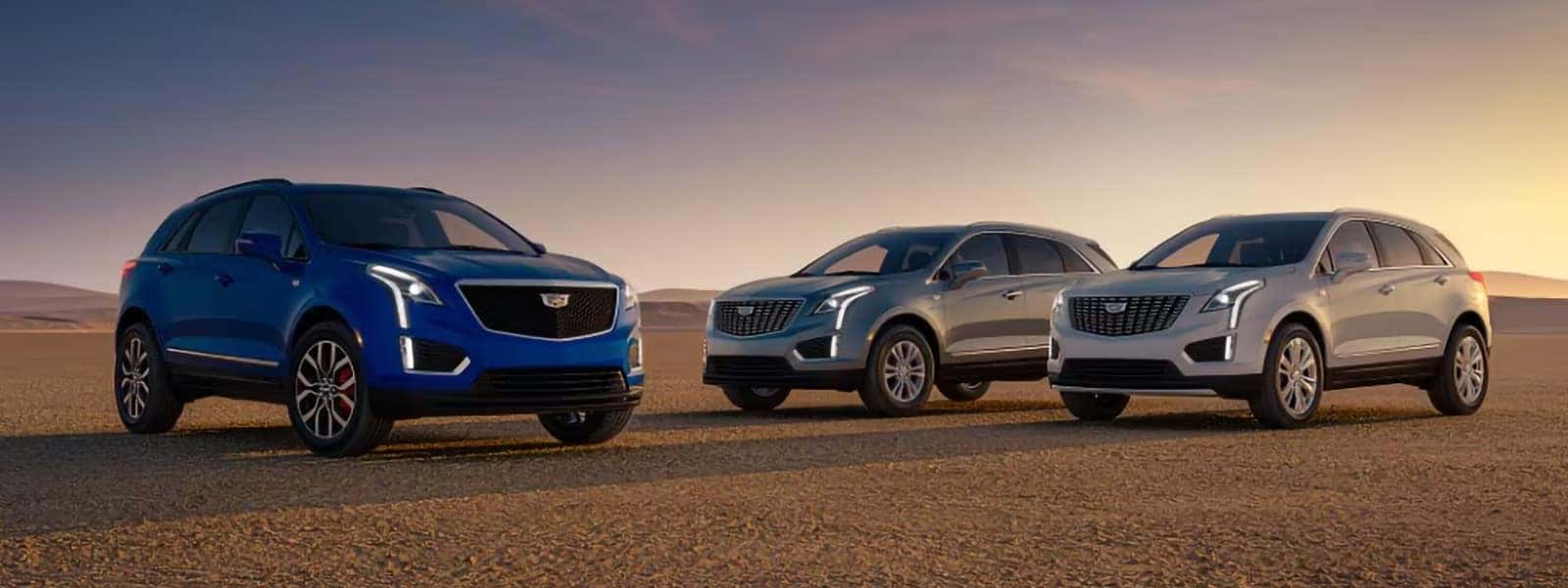2026 Cadillac XT5 SUVs in three trim levels parked in a desert landscape at sunset
