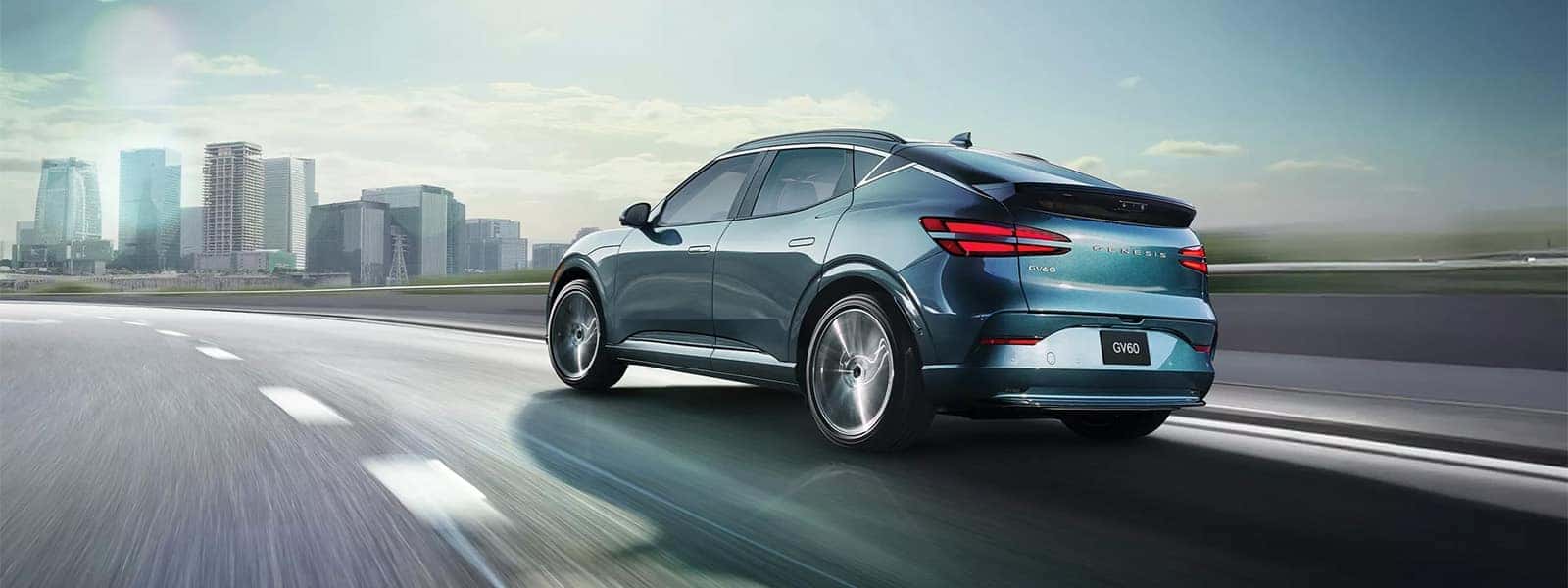 2026 Genesis GV60 electric luxury SUV driving on a city highway with rear exterior styling, sloping roofline, and LED taillights