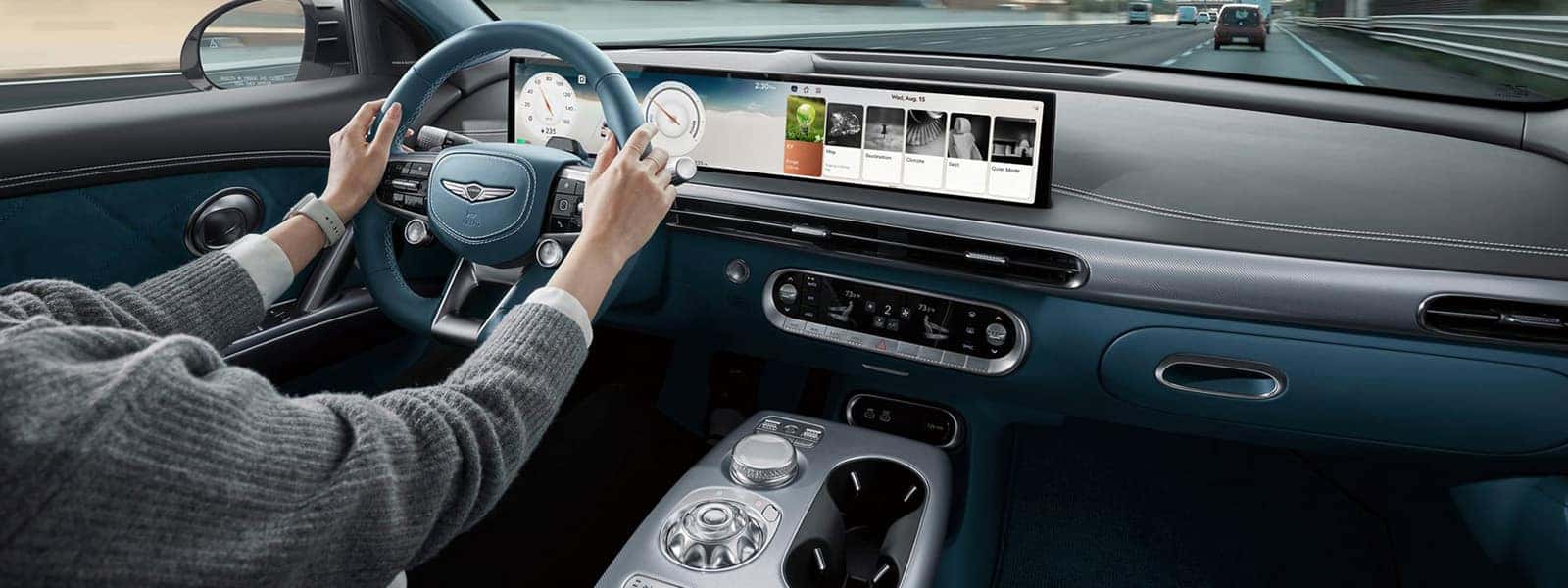 2026 Genesis GV60 interior with wide OLED display, blue steering wheel, and advanced electric SUV technology