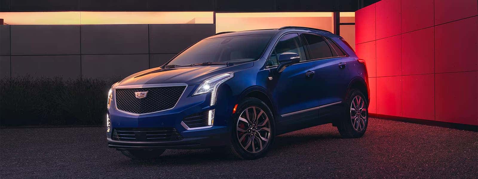 Blue 2026 Cadillac XT5 parked outside a modern building with front grille, LED lighting, and luxury SUV exterior styling visible