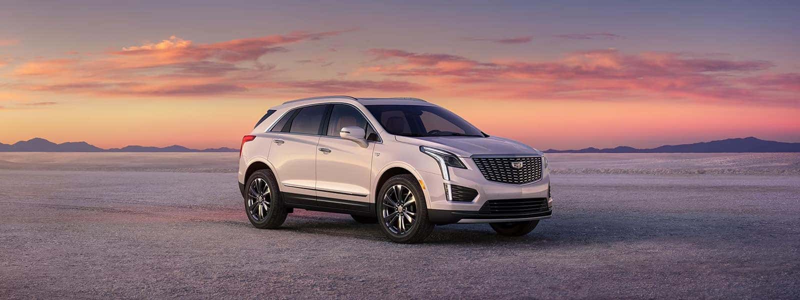 2026 Cadillac XT5 luxury SUV parked on a desert landscape at sunset with front grille and LED lighting visible