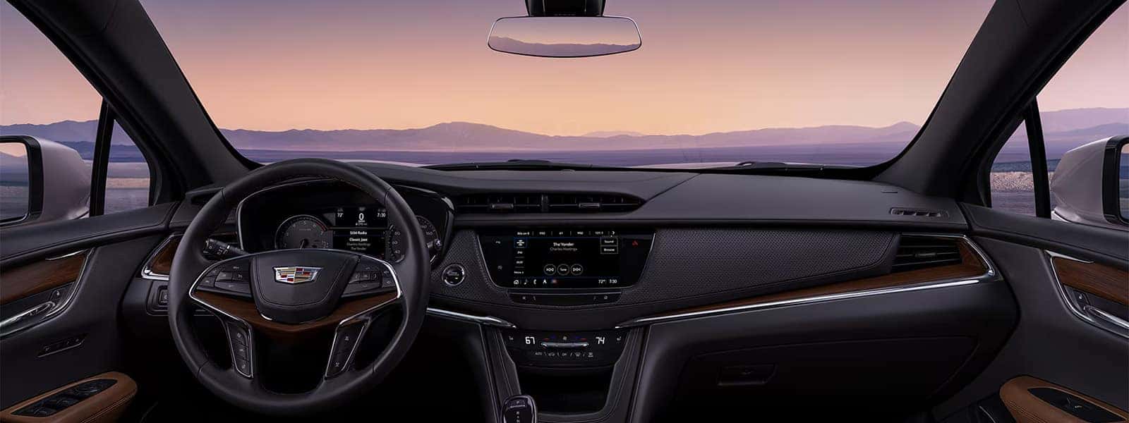 2026 Cadillac XT5 interior cockpit with steering wheel, infotainment screen, driver display, and panoramic windshield view