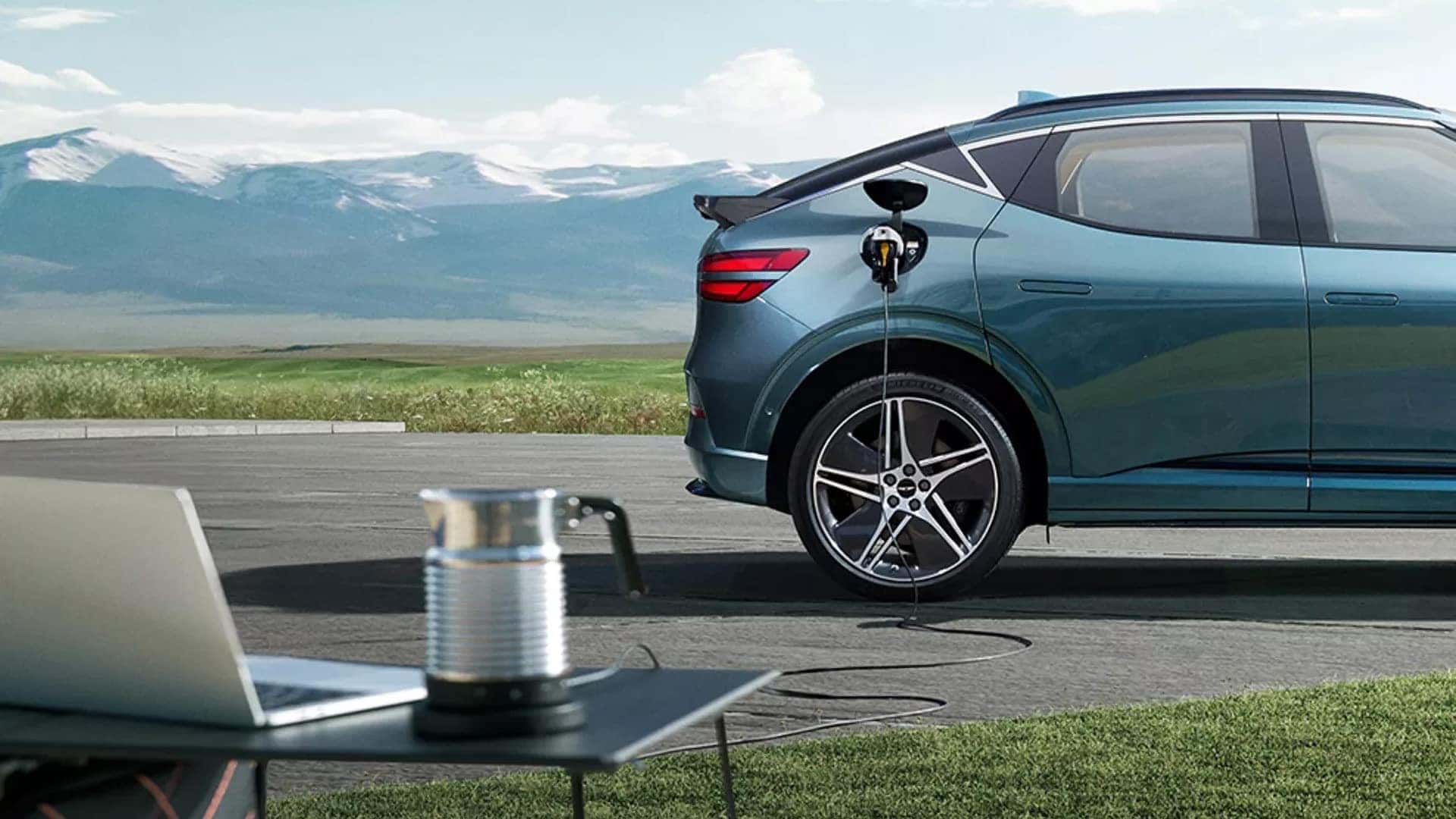 2026 Genesis GV60 charging outdoors with vehicle-to-load power supplying electricity to a campsite setup