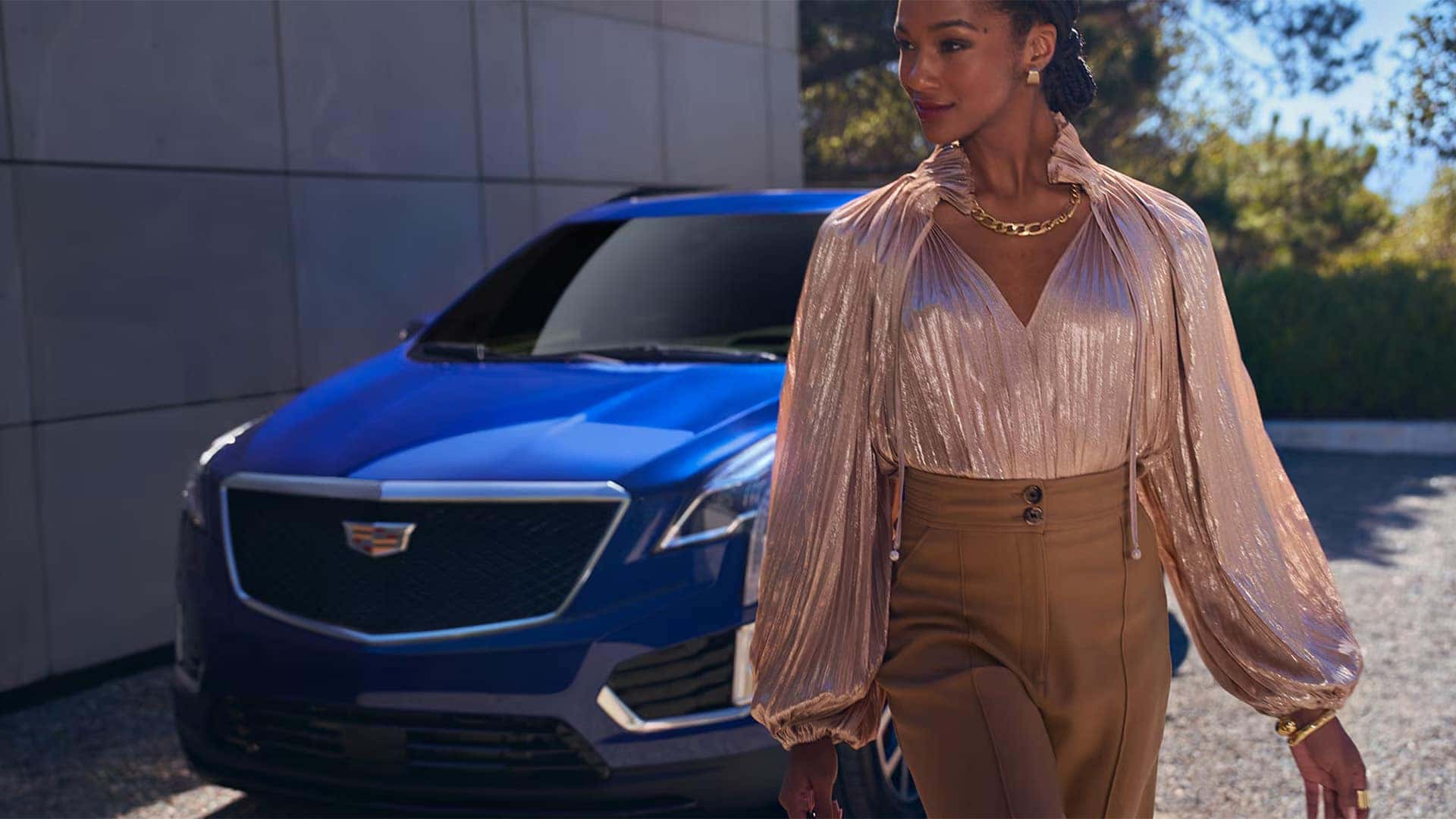 Blue 2026 Cadillac XT5 front exterior with Cadillac grille and headlamp design shown behind a person walking near the SUV