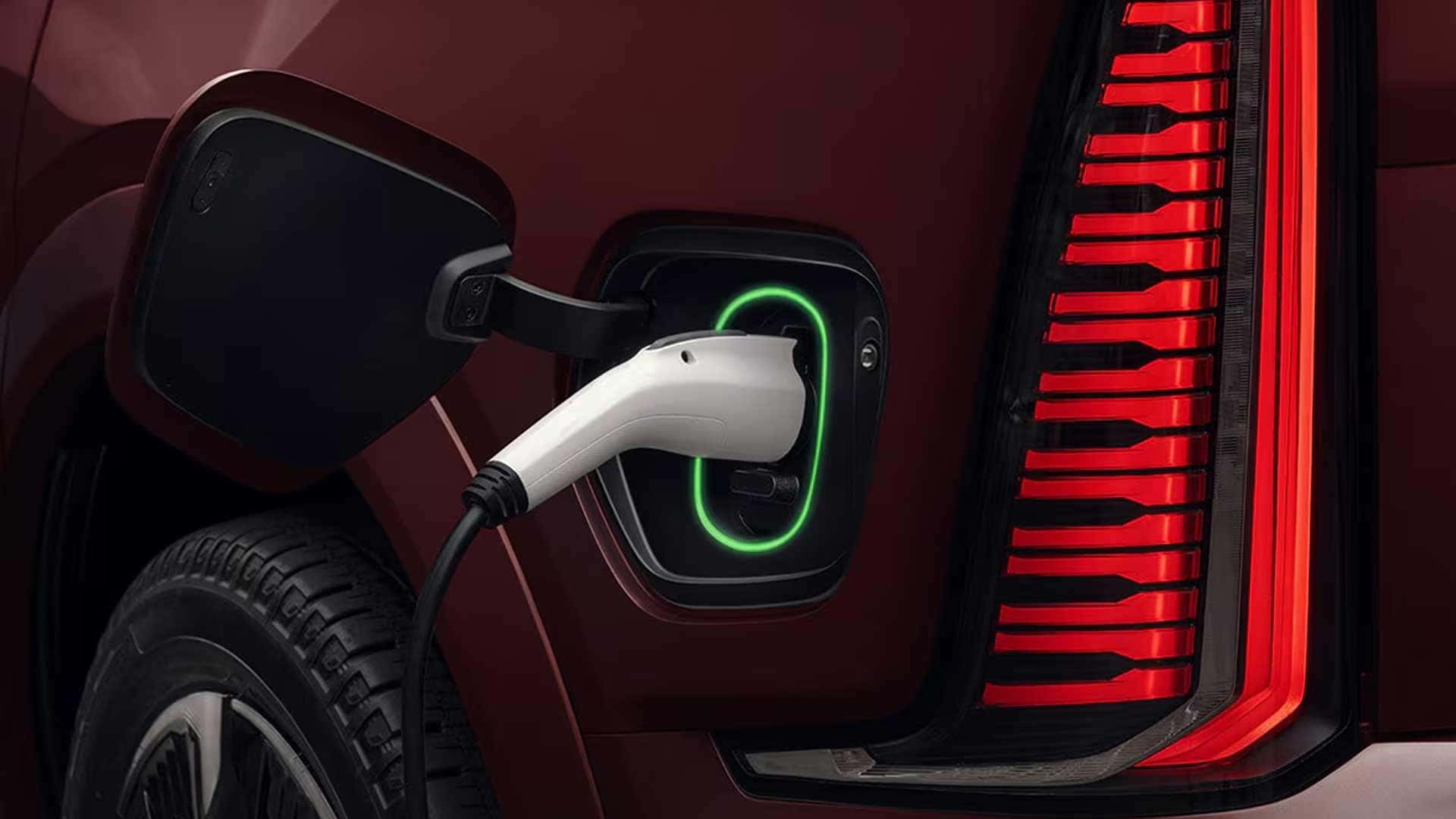 Close-up of charging cable connected to vehicle port beside vertical rear LED taillight