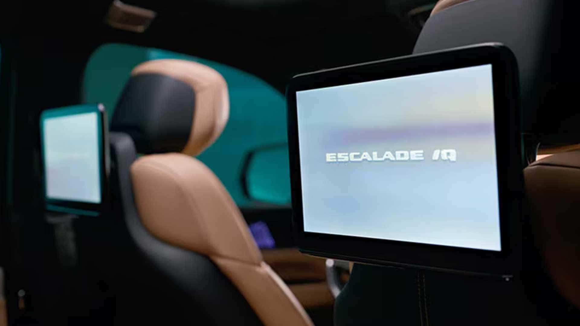 Rear seat entertainment screens mounted behind tan front seats with Escalade IQ shown on one display