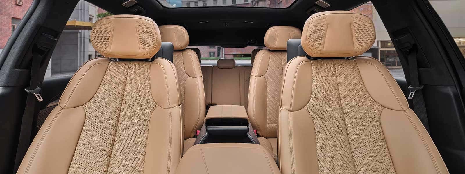 Wide interior view with tan leather seats, second-row chairs, rear bench, and panoramic glass roof