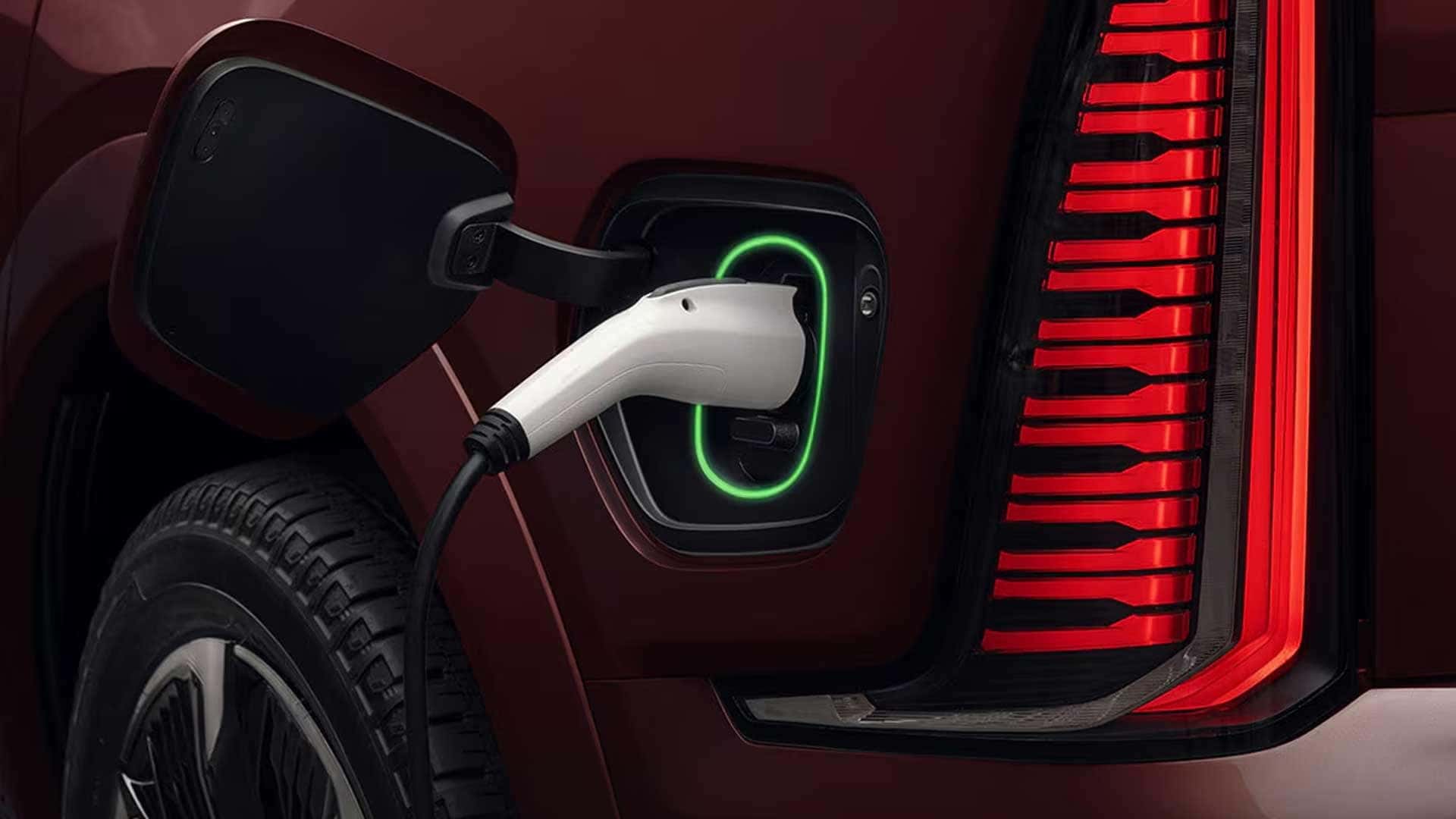 Charging plug connected to Cadillac Escalade IQ port beside vertical red tail light