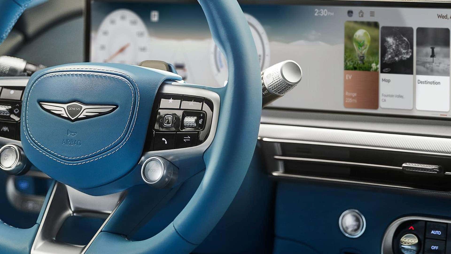 Close-up of 2026 Genesis GV60 steering wheel and wide OLED display with EV range, maps, and infotainment menus