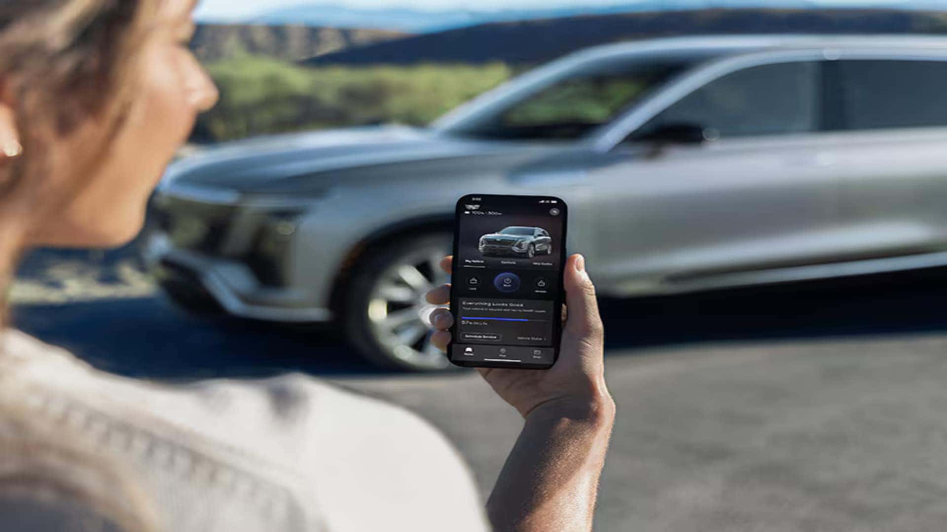 Driver using the myCadillac app near a 2026 Cadillac VISTIQ electric SUV for connected vehicle features