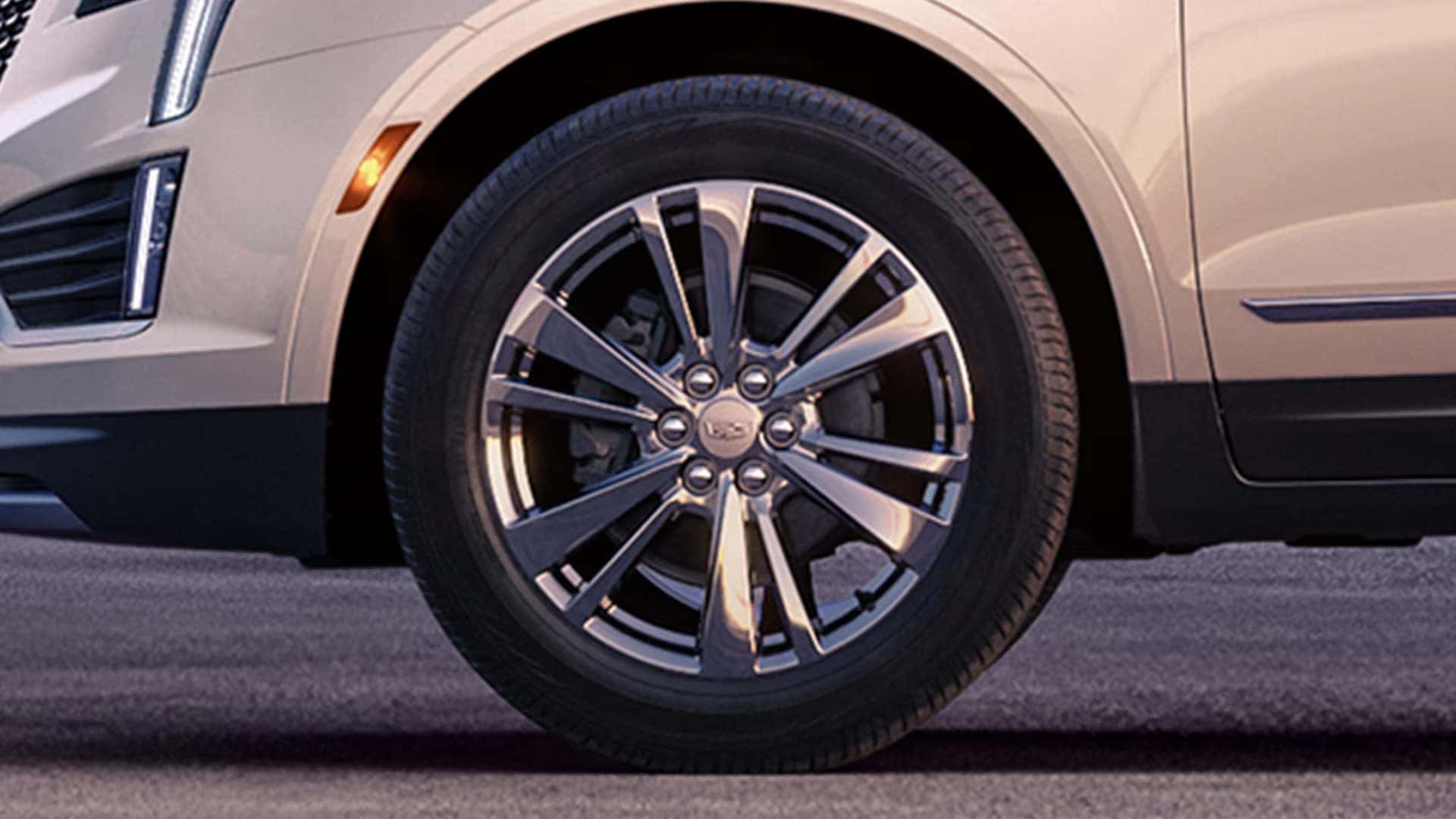 Close up of 2026 Cadillac XT5 alloy wheel with front lighting and lower exterior trim visible