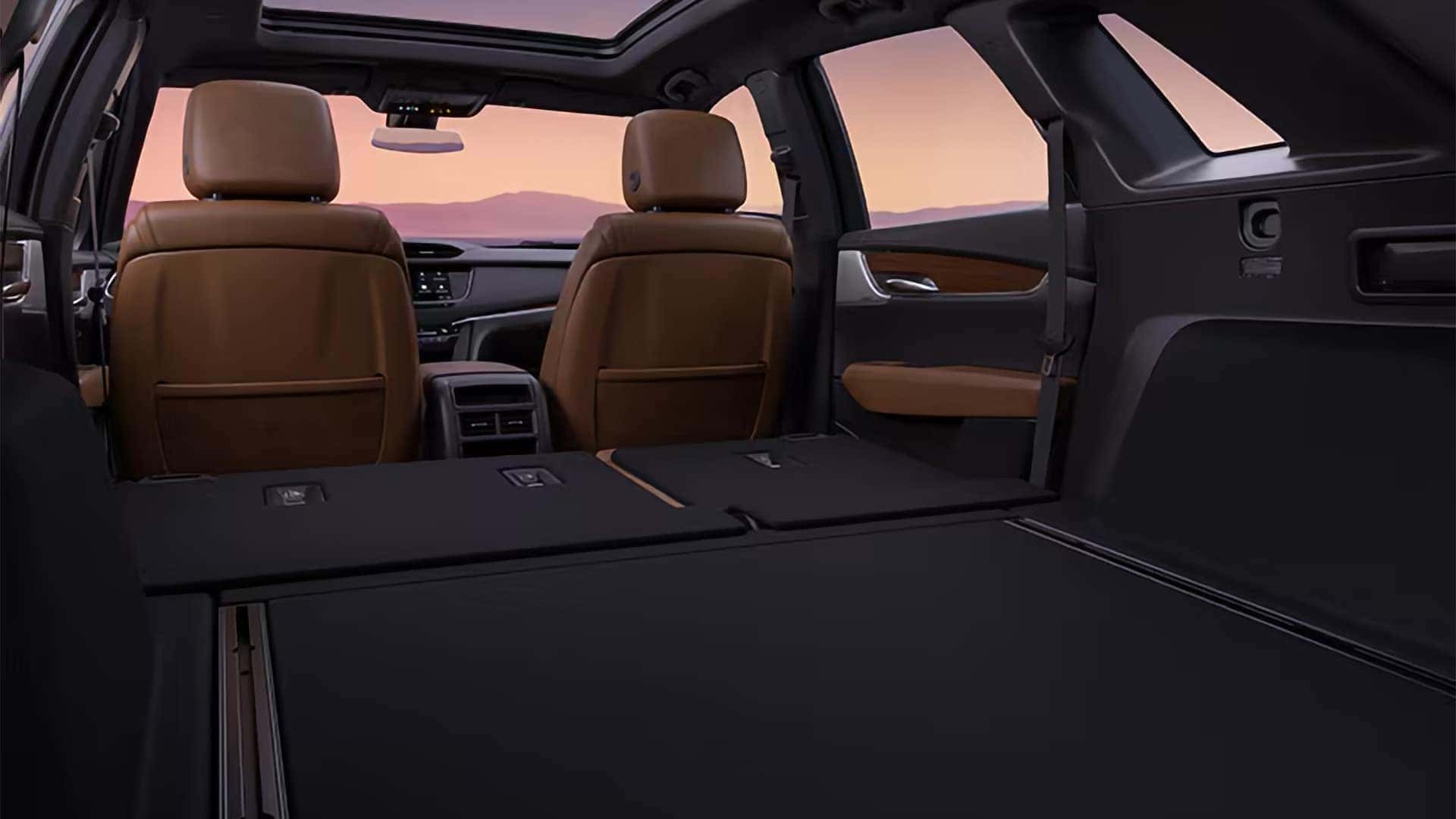2026 Cadillac XT5 cargo area with rear seats folded flat, panoramic sunroof, and expanded storage space