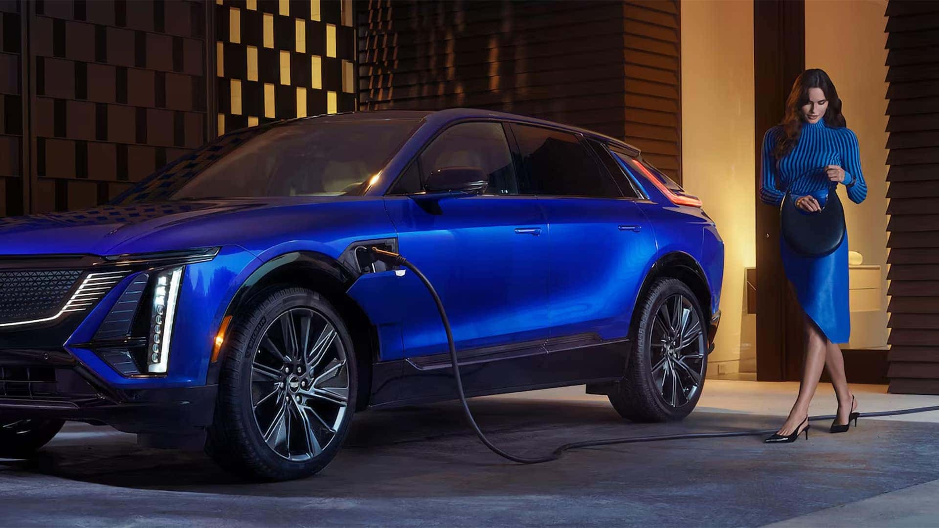 Blue 2026 Cadillac LYRIQ electric SUV charging at a home or destination charger with luxury exterior details visible