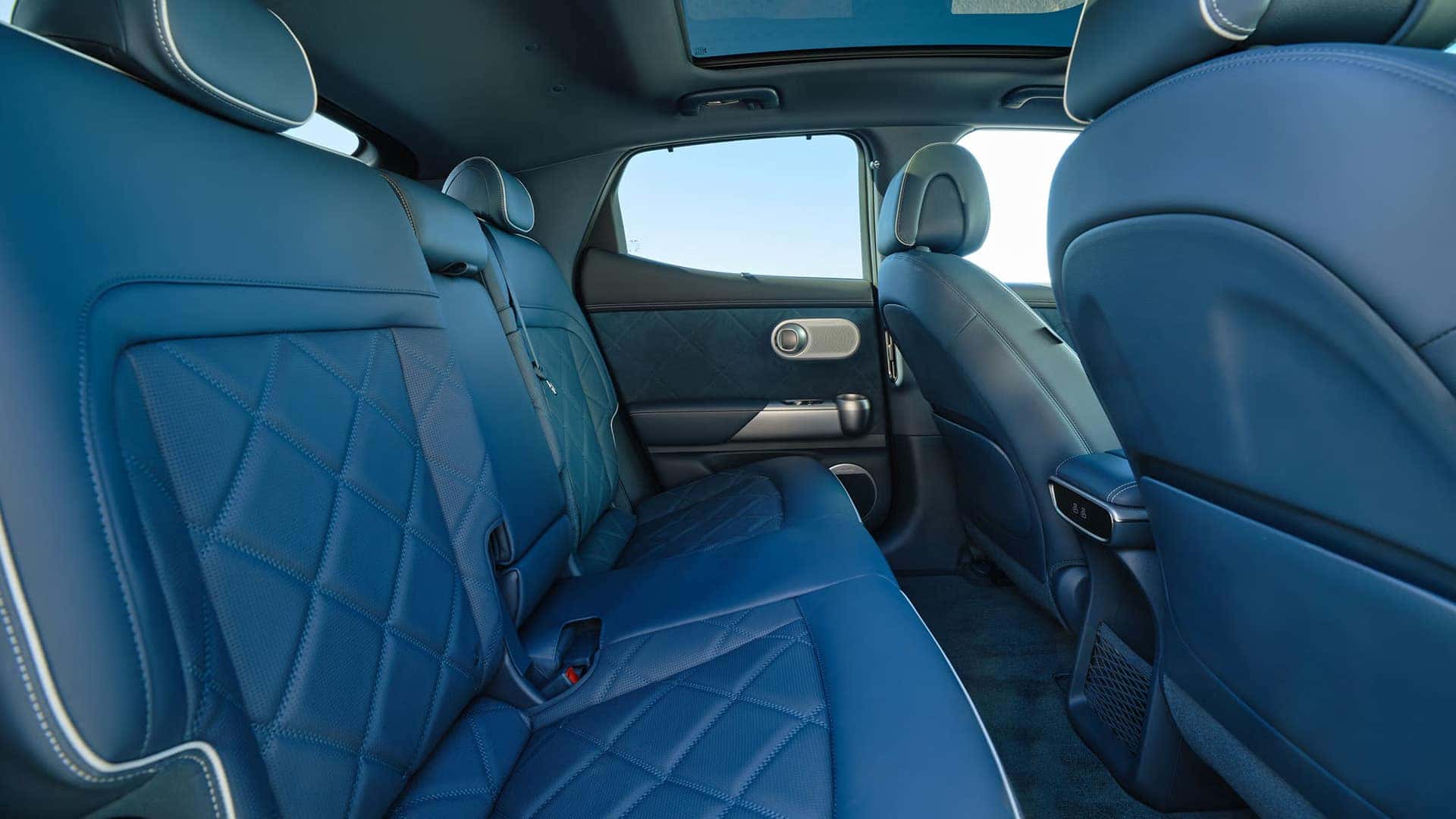 2026 Genesis GV60 rear passenger seating with blue quilted upholstery, spacious second row, and glass roof