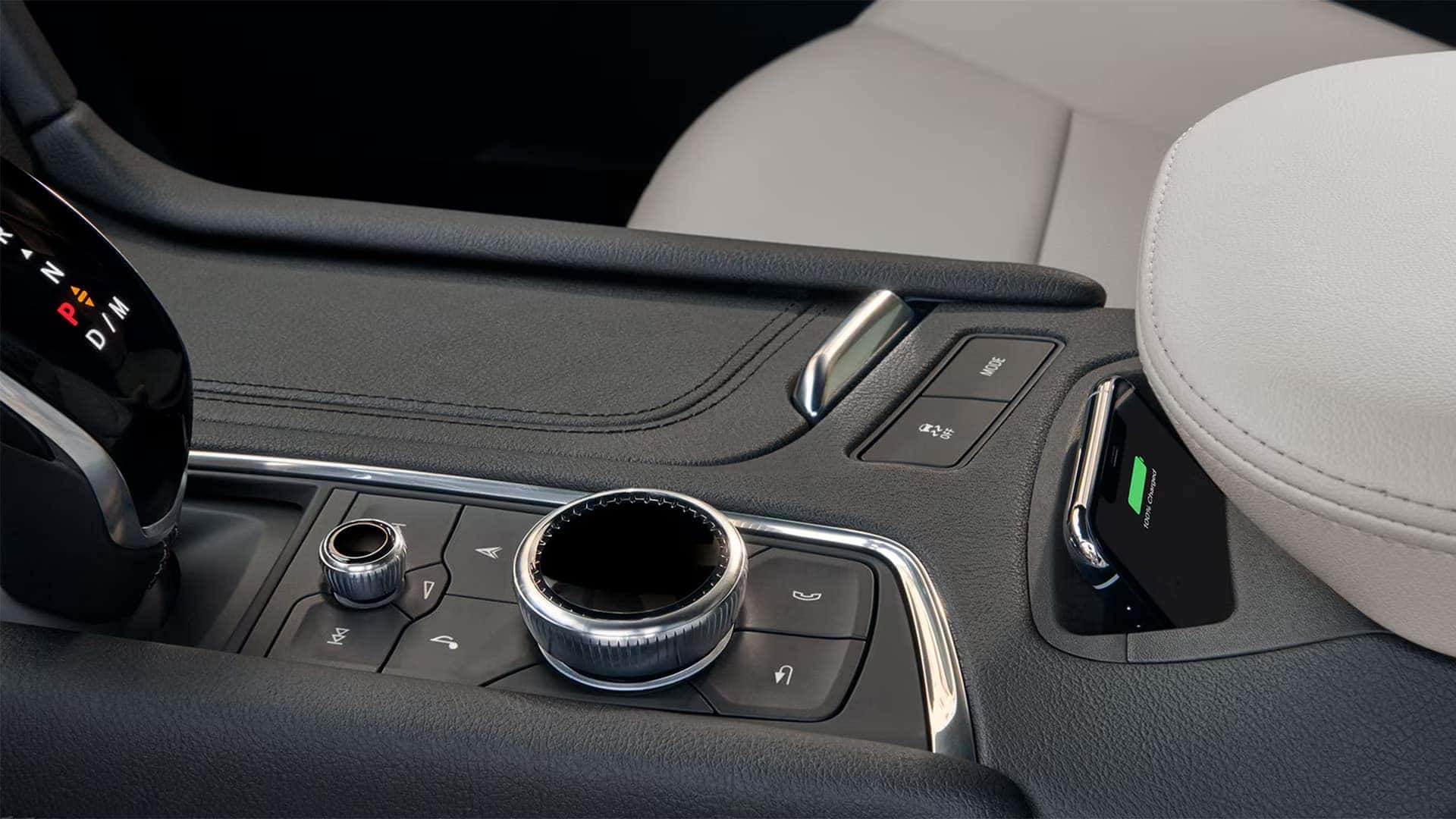 2026 Cadillac XT5 center console with wireless phone charging pad, rotary controls, drive mode button, and leather trim