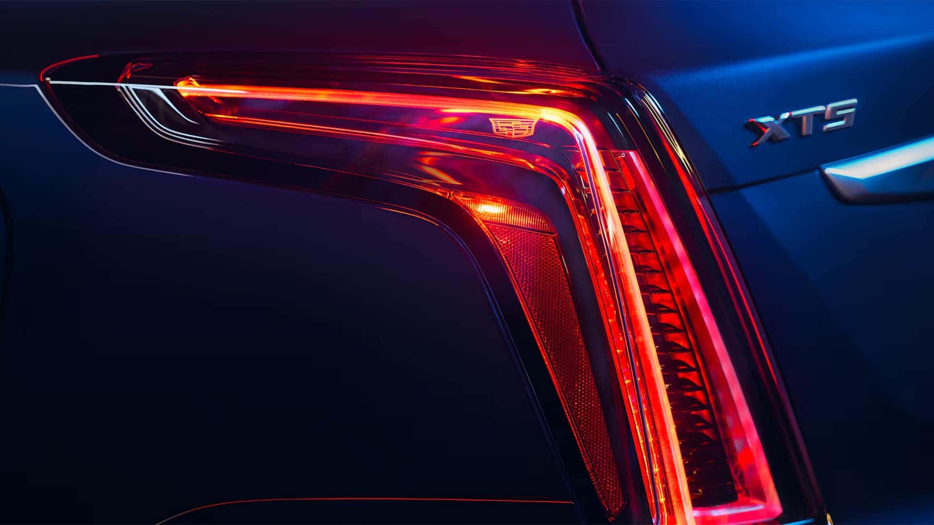 Close up of 2026 Cadillac XT5 rear LED taillamp and XT5 badge on blue exterior
