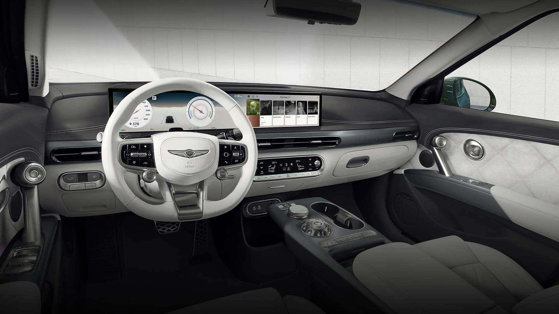 2026 Genesis GV60 interior with white steering wheel, wide digital display, center console, and quilted door trim