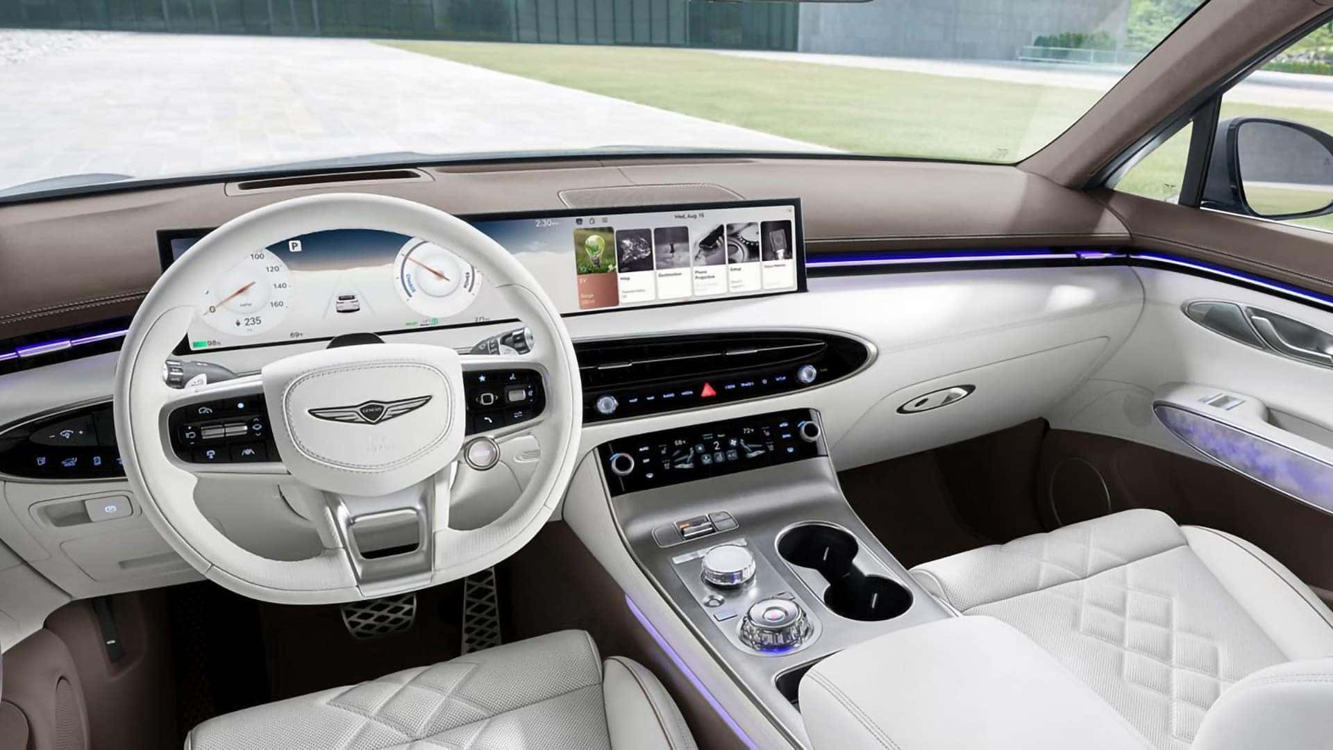 Driver view of the 2026 Genesis Electrified GV70 cabin with white steering wheel, center console, and panoramic digital display