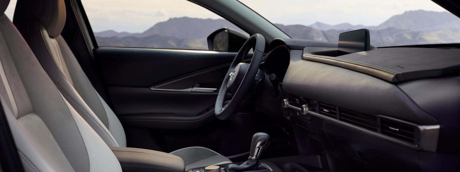 Front cabin of the 2026 Mazda CX-30 with light-colored seats, a driver-focused dashboard, and center display