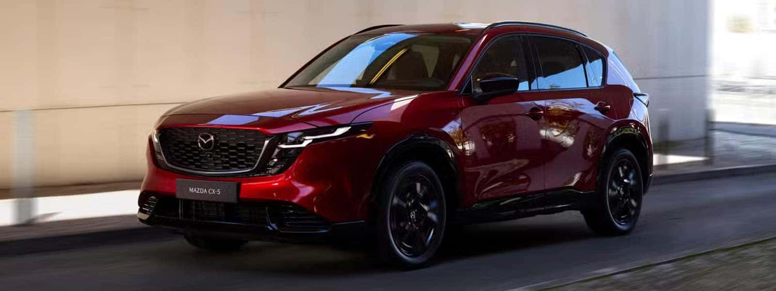 Red 2026 Mazda CX-5 driving through a modern urban setting