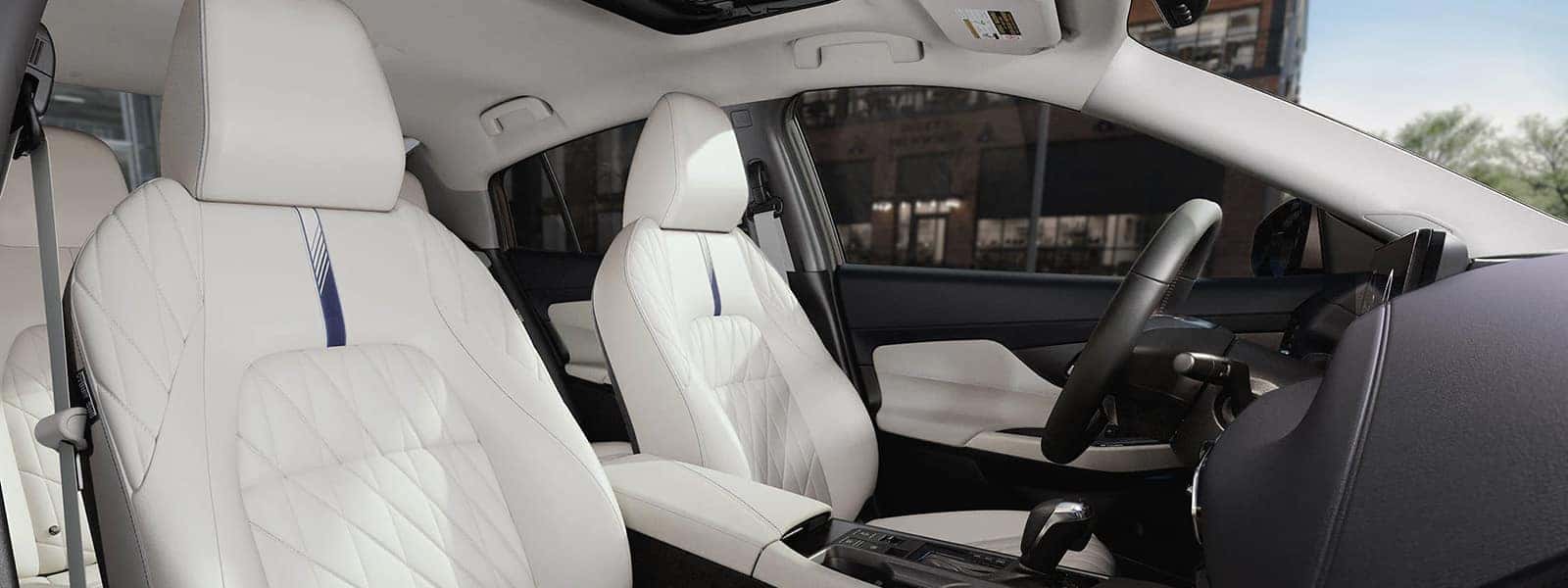 2026 Nissan Sentra interior with quilted white front seats, center console, steering wheel, and panoramic moonroof