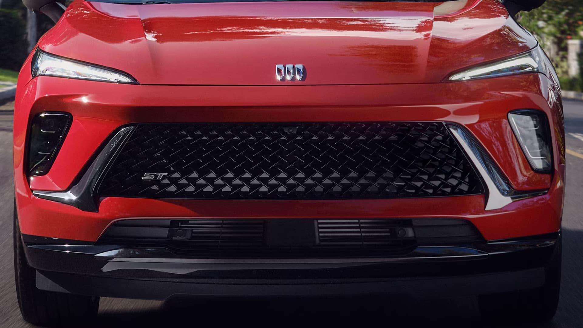 Close-up of the red 2026 Buick Envision Sport Touring black mesh grille and Buick emblem