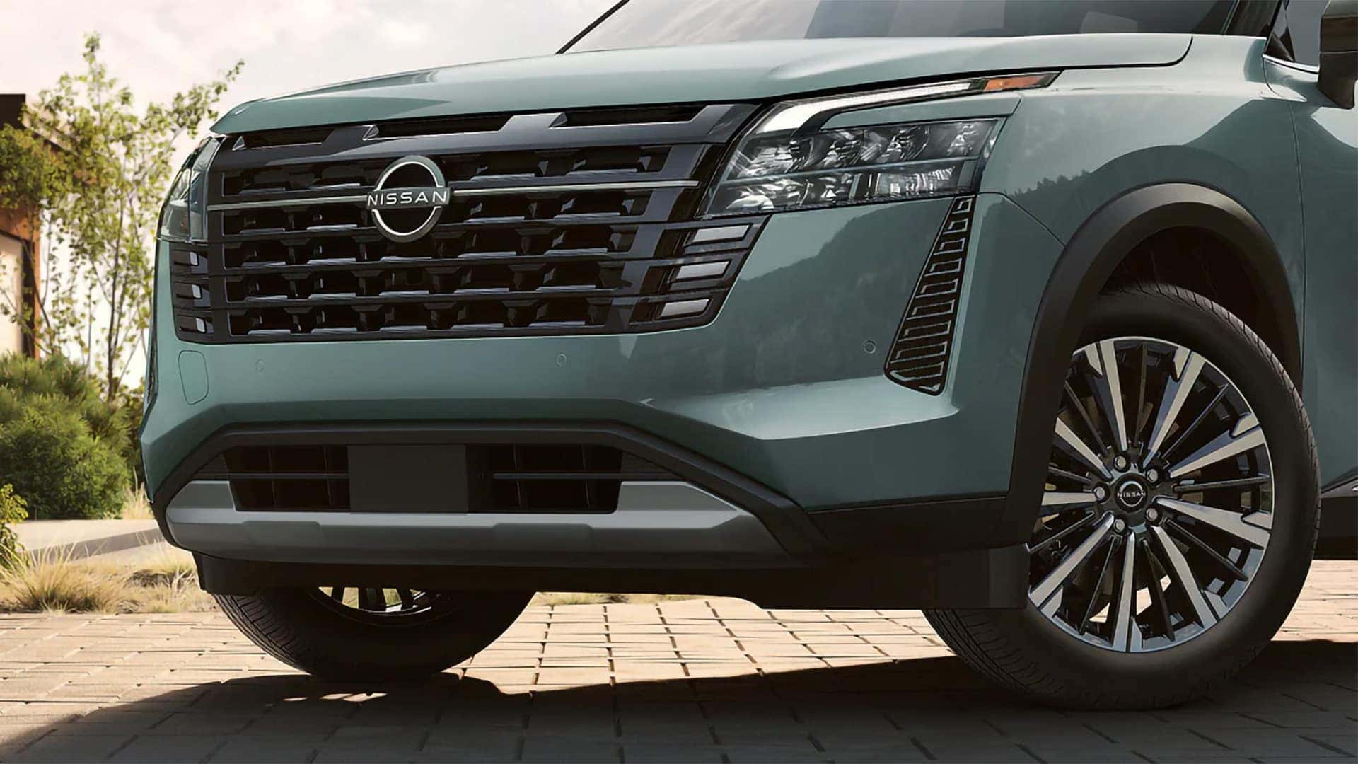 Close-up of the 2026 Nissan Pathfinder front grille, Nissan emblem, LED lighting, and alloy wheel