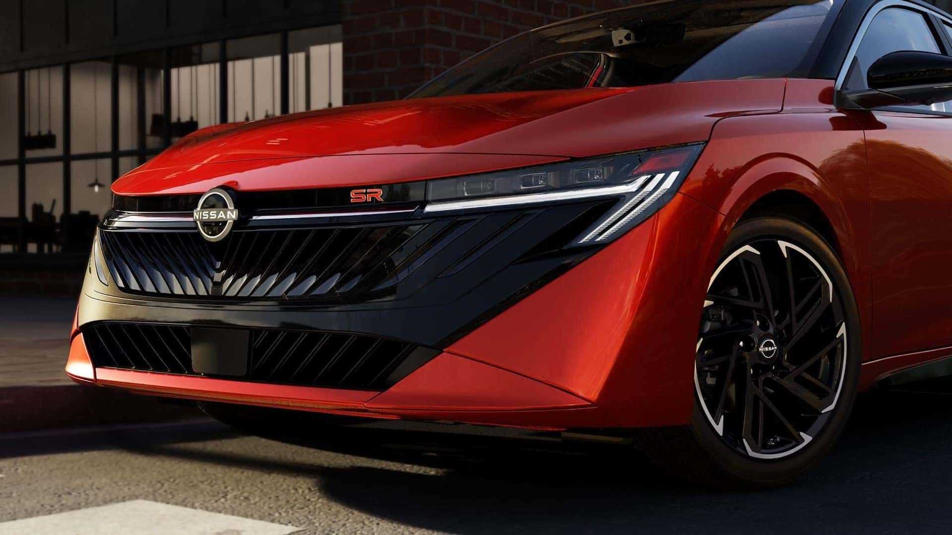 Close-up of the red 2026 Nissan Sentra SR grille, Nissan emblem, LED headlight, and front wheel