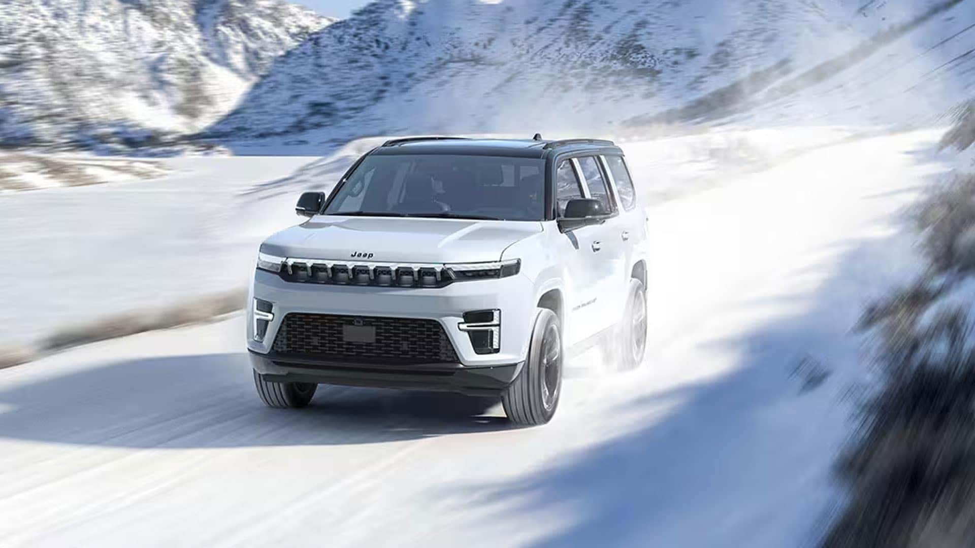 White Grand Wagoneer driving on a snow-covered mountain road with snow spraying around the tires.