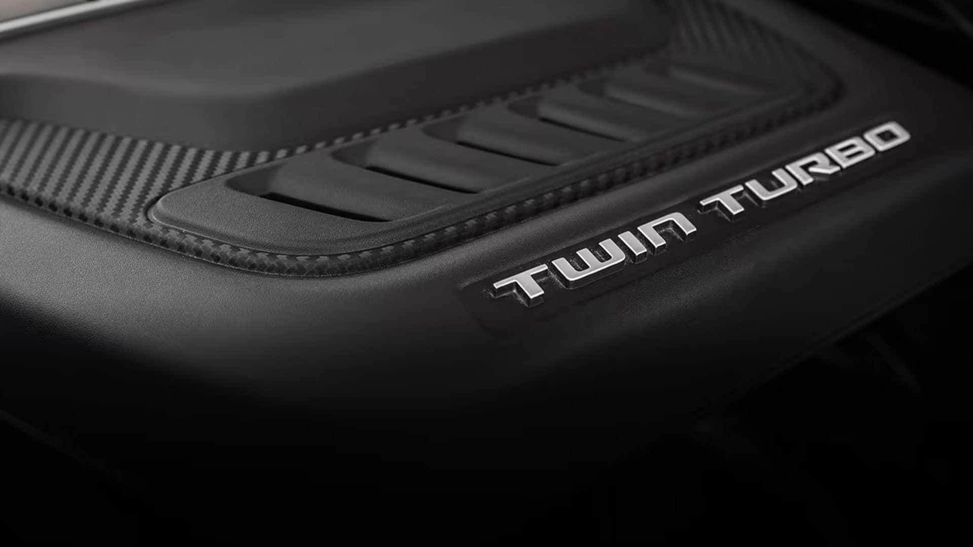 2026 Jeep Grand Wagoneer engine cover close-up with silver Twin Turbo lettering and textured black trim.