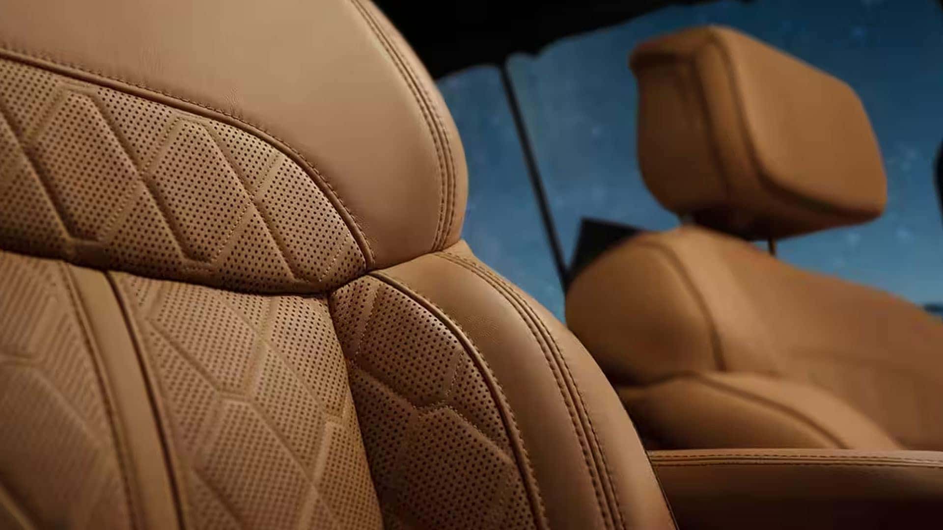Close-up of tan leather seats with perforated diamond-pattern inserts inside a 2026 Jeep Grand Wagoneer.