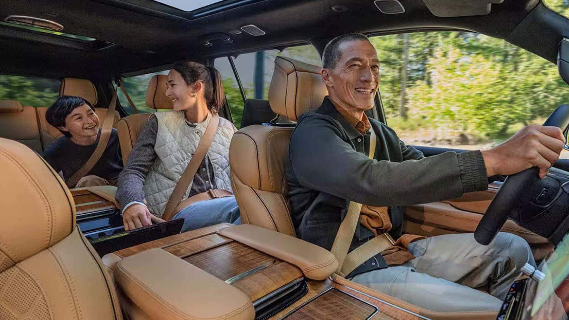 Interior of a 2026 Jeep Grand Wagoneer with tan seats, a driver, a second-row passenger, and a rear passenger.