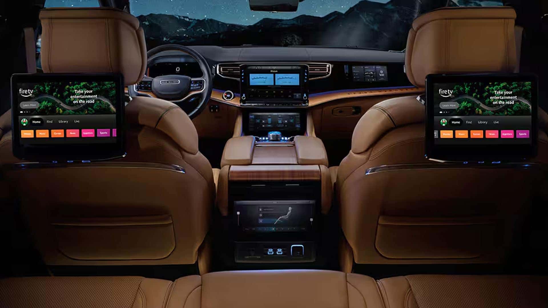 Rear cabin of a 2026 Jeep Grand Wagoneer with tan seats and two seatback entertainment screens displaying Fire TV.