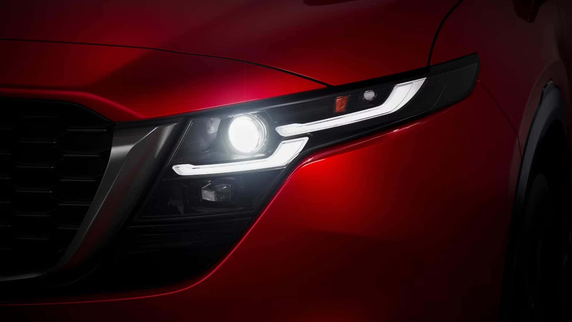 Close-up of an illuminated headlight on a red 2026 Mazda CX-5