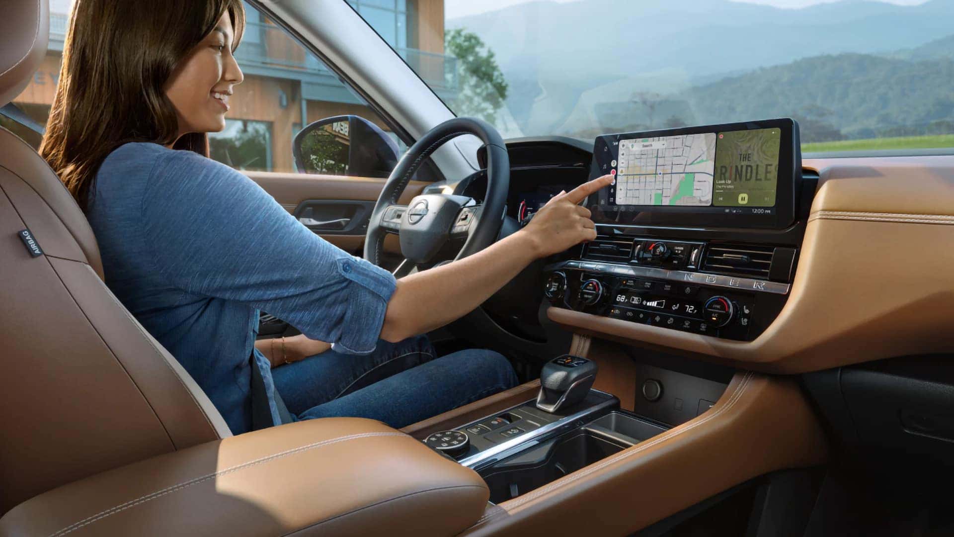 2026 Nissan Pathfinder driver using the touchscreen navigation and audio display