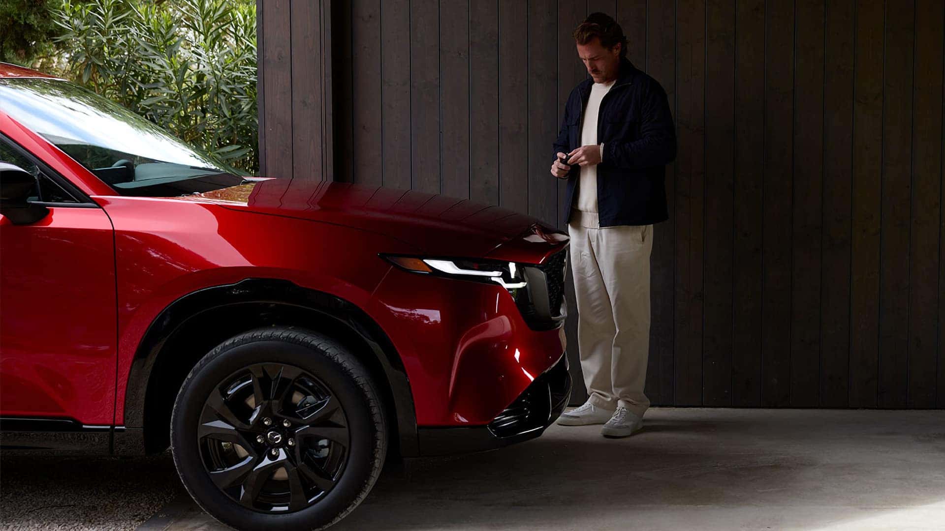 Red 2026 Mazda CX-5 showing a black alloy wheel and illuminated front lighting