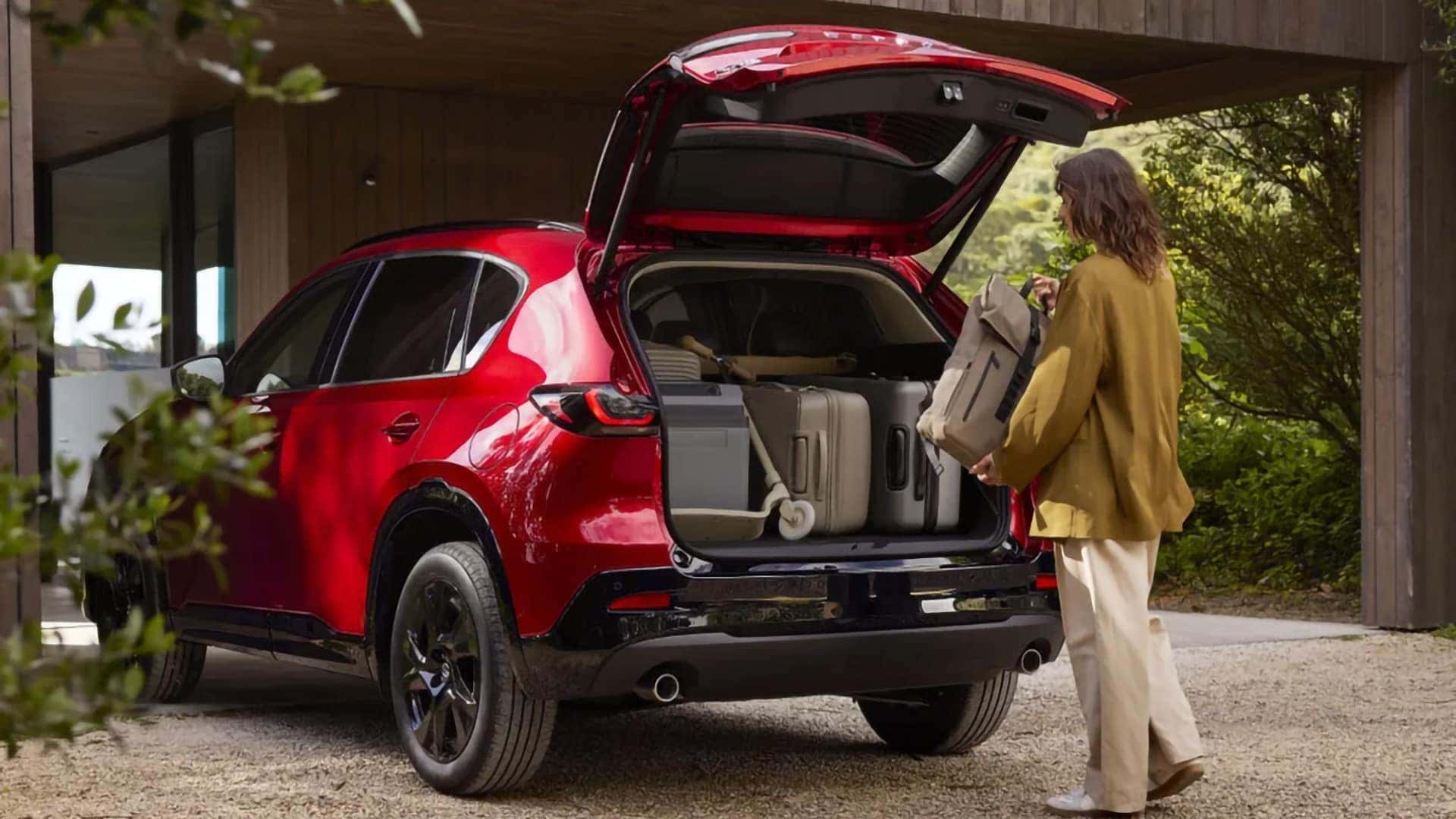 Woman loading luggage into the cargo area of a red 2026 Mazda CX-5