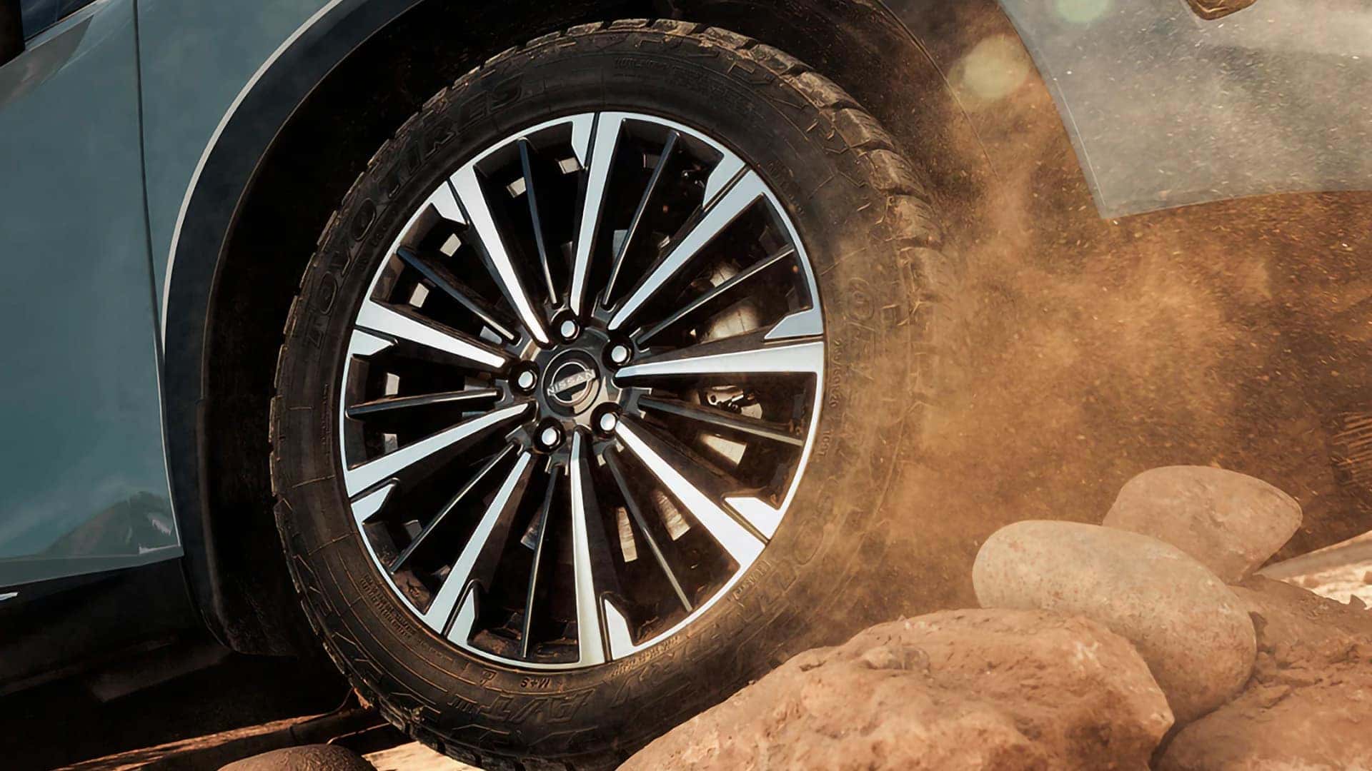 Close-up of a 2026 Nissan Pathfinder aluminum-alloy wheel and tire traveling over rocky terrain