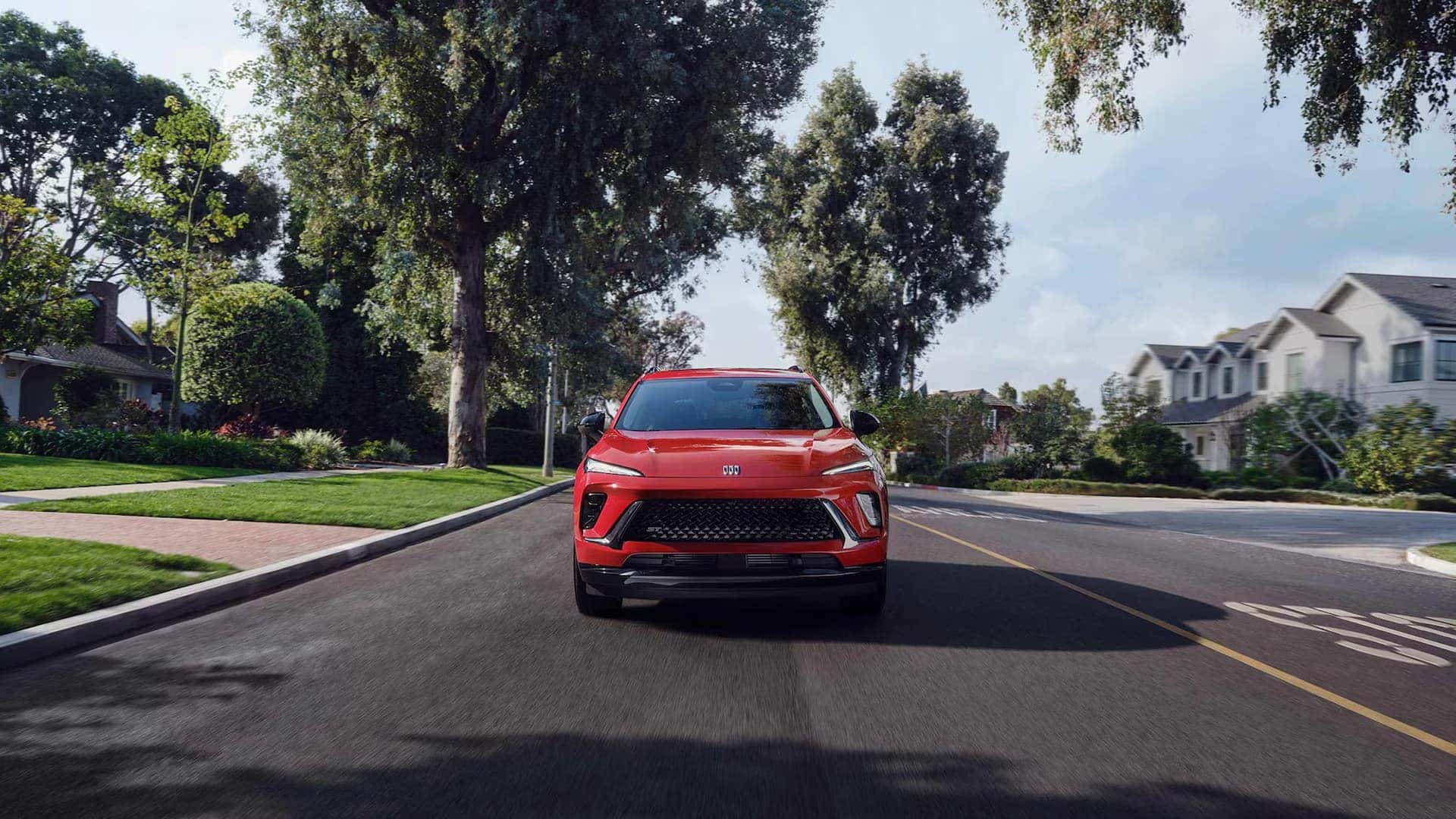 Red 2026 Buick Envision driving through a residential neighborhood