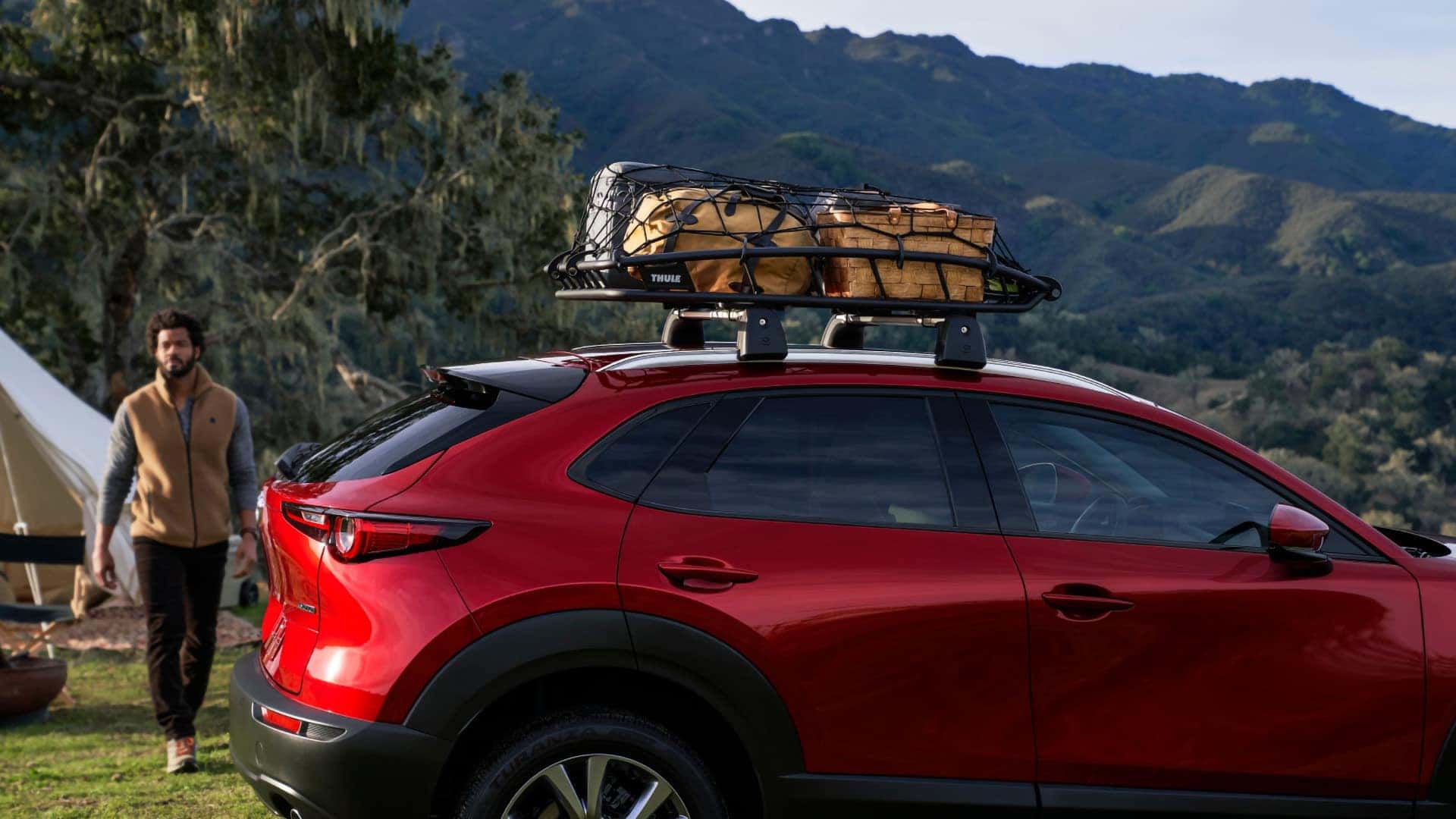 Red 2026 Mazda CX-30 at a mountain campsite with luggage secured in a rooftop cargo basket