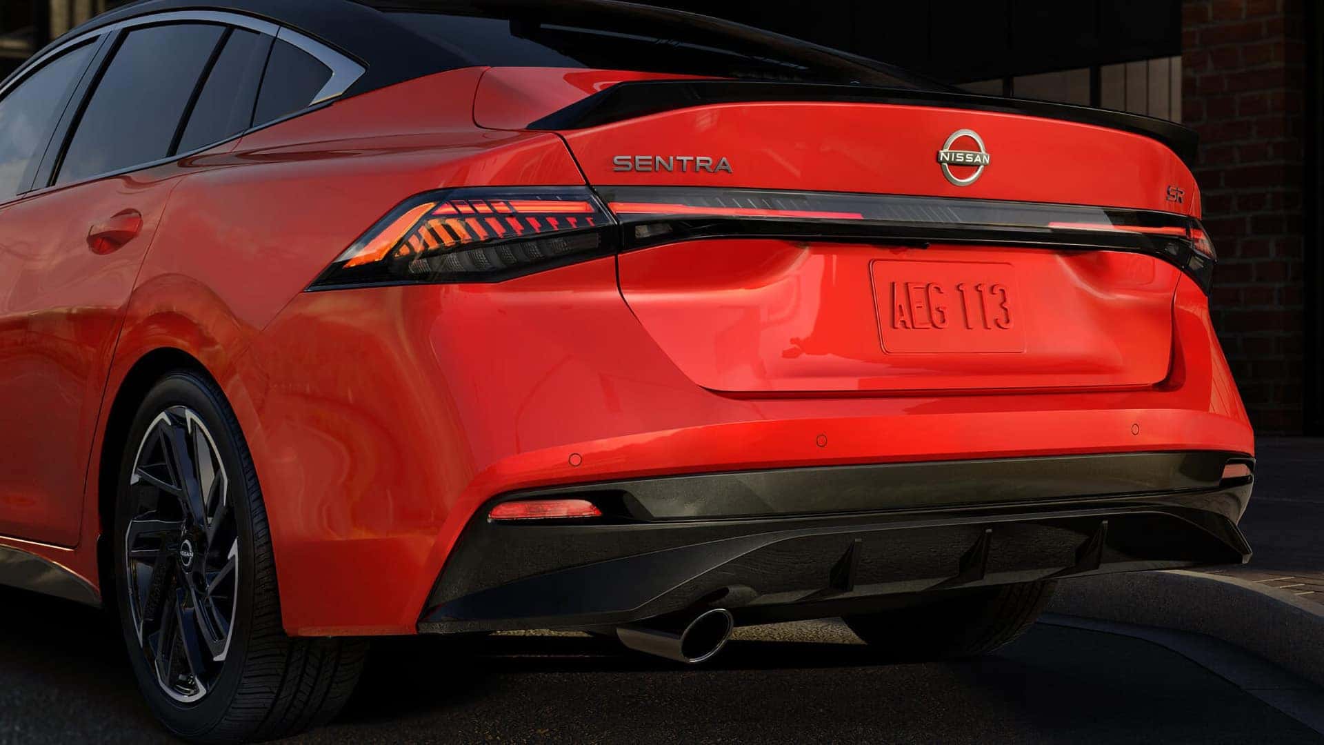 Rear three-quarter view of the red 2026 Nissan Sentra SR showing its LED taillights, spoiler, and rear bumper