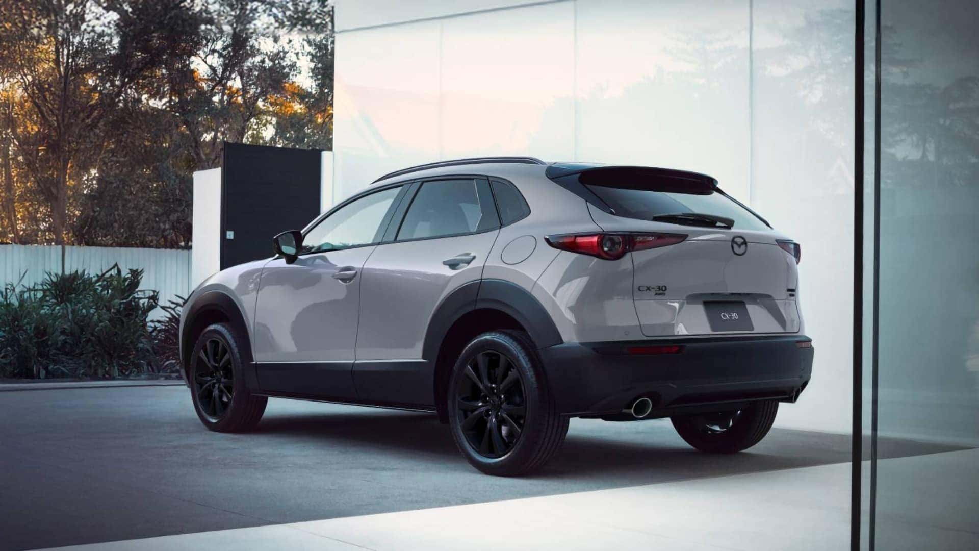 Rear three-quarter view of a light gray 2026 Mazda CX-30 with black wheels and exterior cladding