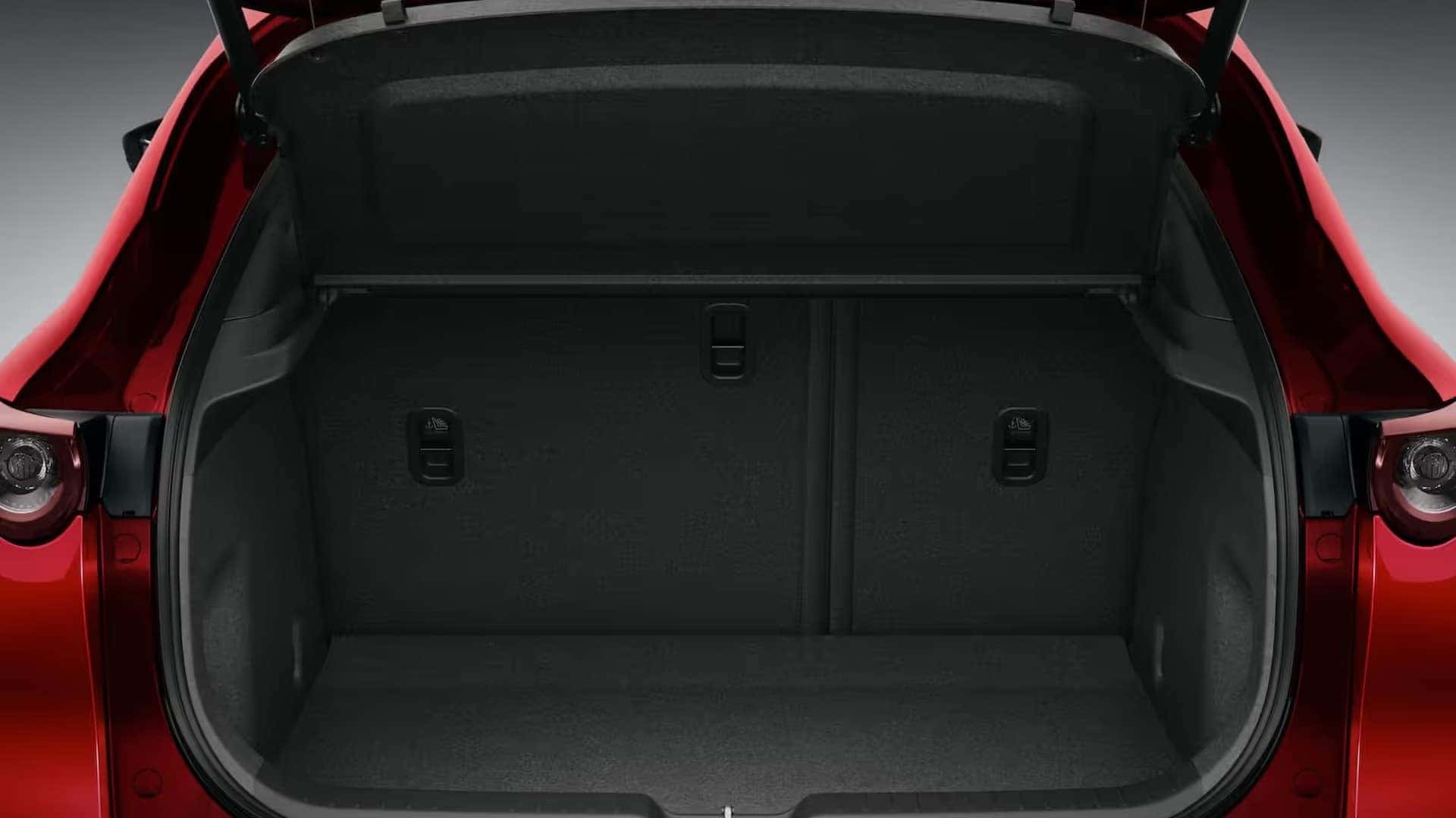 Open cargo area of a red 2026 Mazda CX-30 with an adjustable cargo cover and rear seatbacks