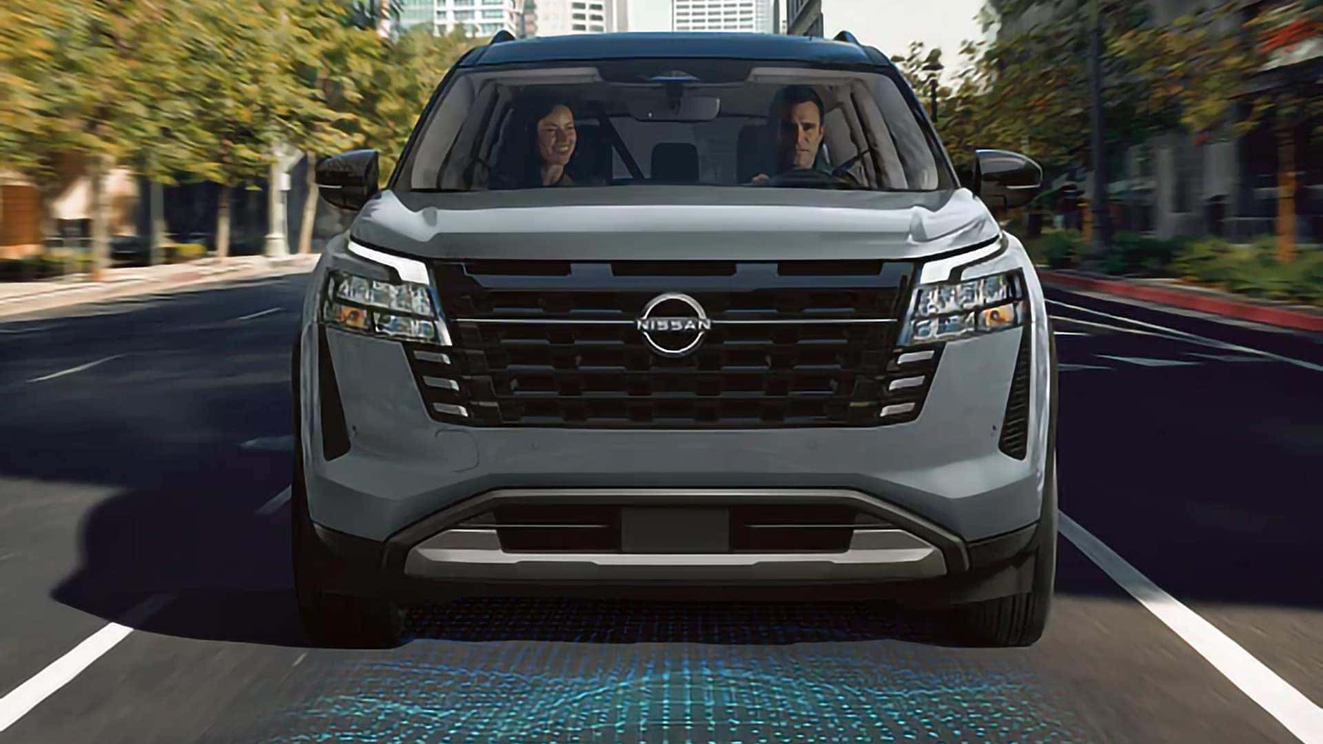Front view of a 2026 Nissan Pathfinder driving through a city with safety technology illustrated beneath it