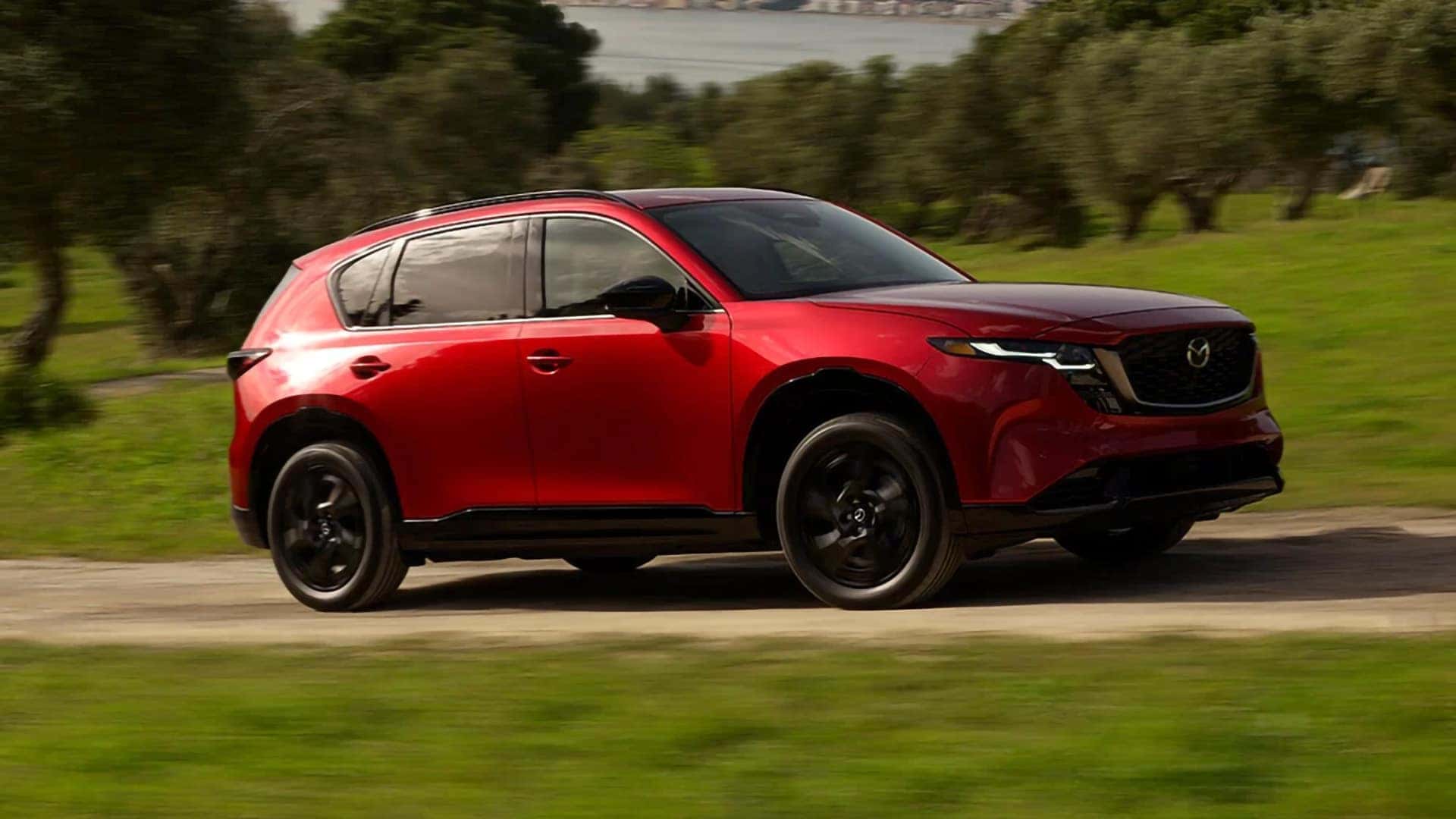Red 2026 Mazda CX-5 driving in front three-quarter view with black alloy wheels