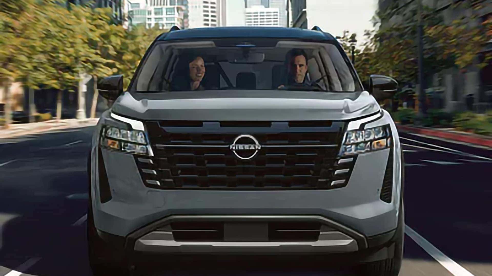 Front view of a 2026 Nissan Pathfinder driving through a city with LED daytime running lights illuminated