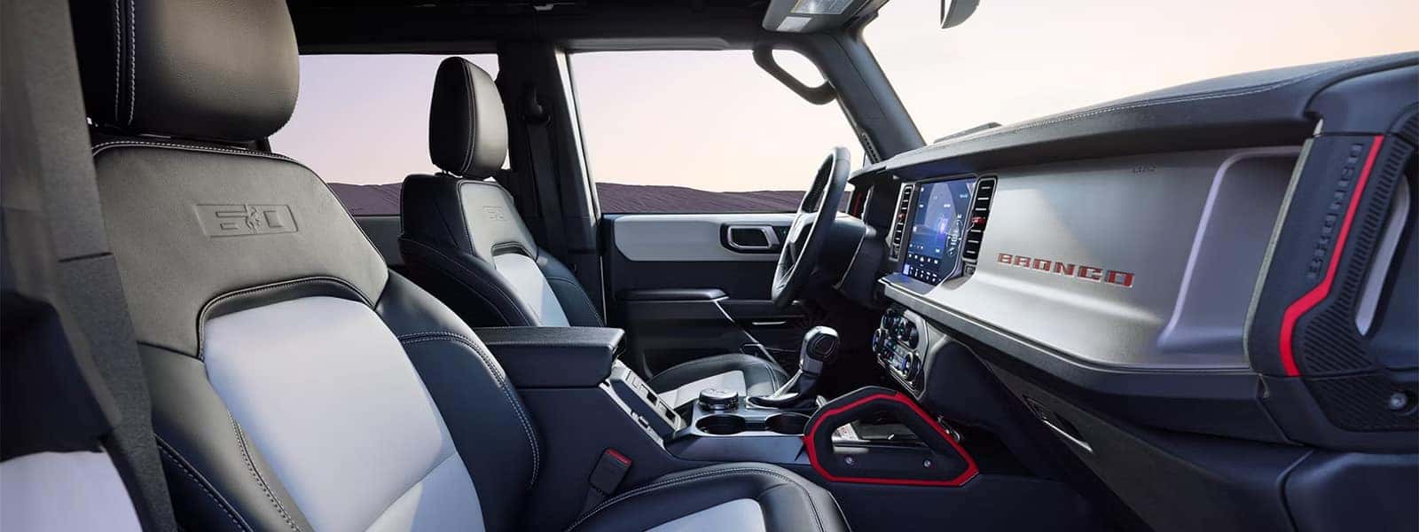 2026 Ford Bronco interior with two-tone front seats, center touchscreen, and red dashboard accents