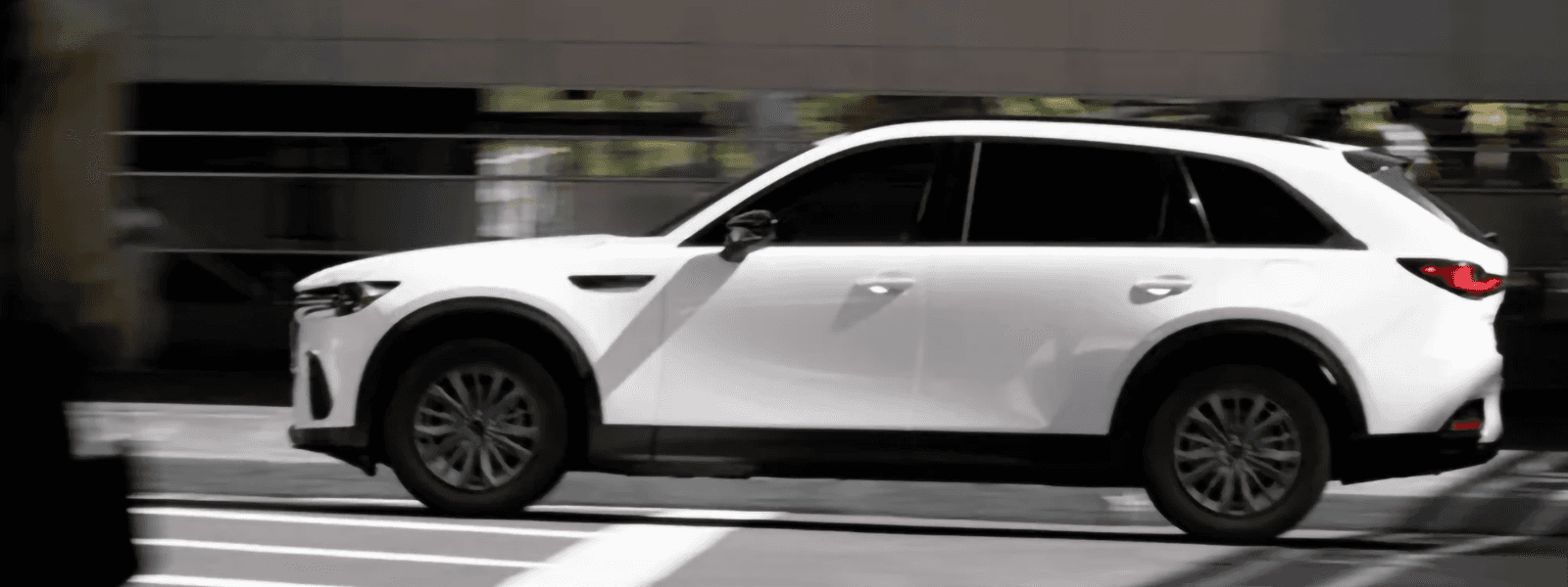 White 2026 Mazda CX-70 PHEV driving through a modern city setting