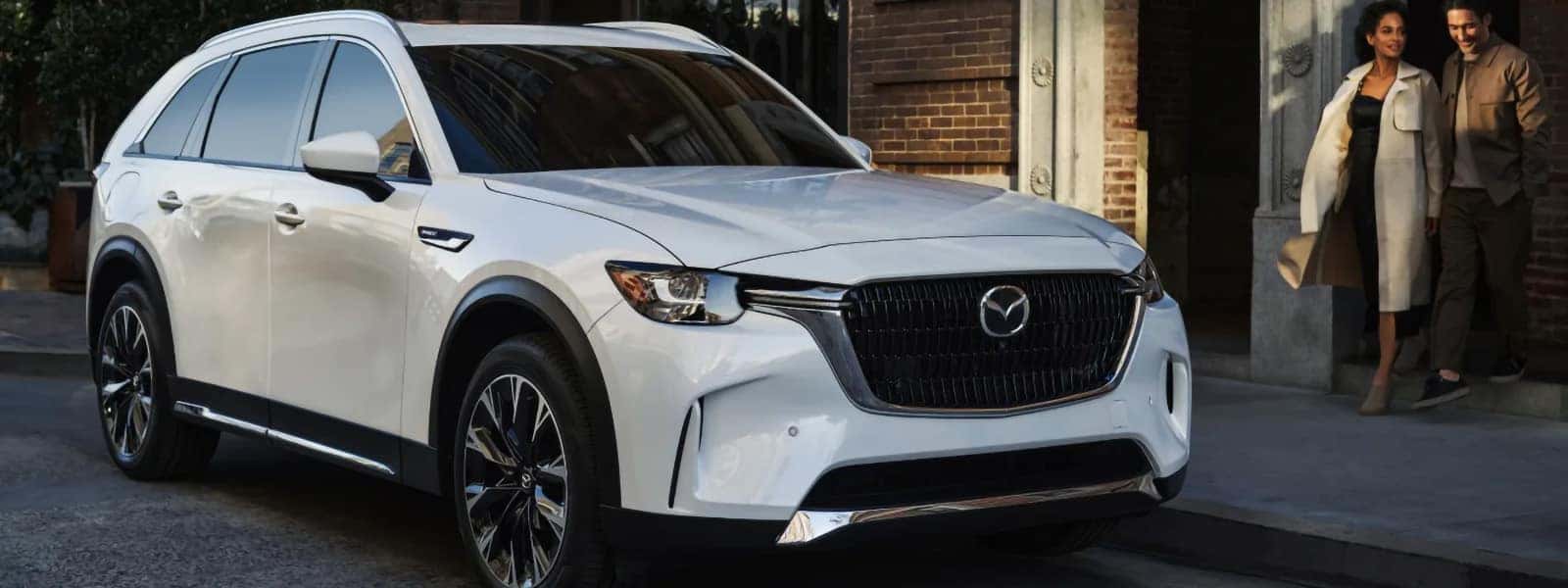White 2026 Mazda CX-90 PHEV shown from the front three-quarter angle outside a city building