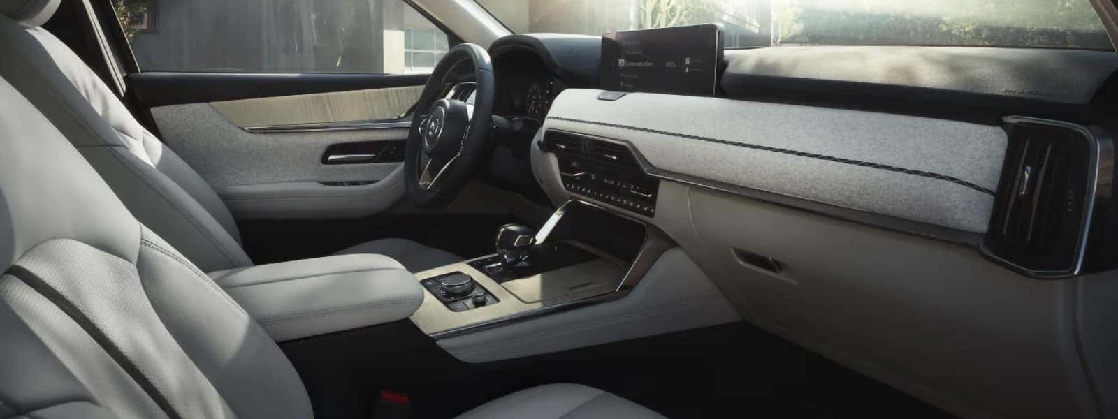 Light-colored 2026 Mazda CX-90 PHEV cabin with front seats, a wide dashboard, and center console